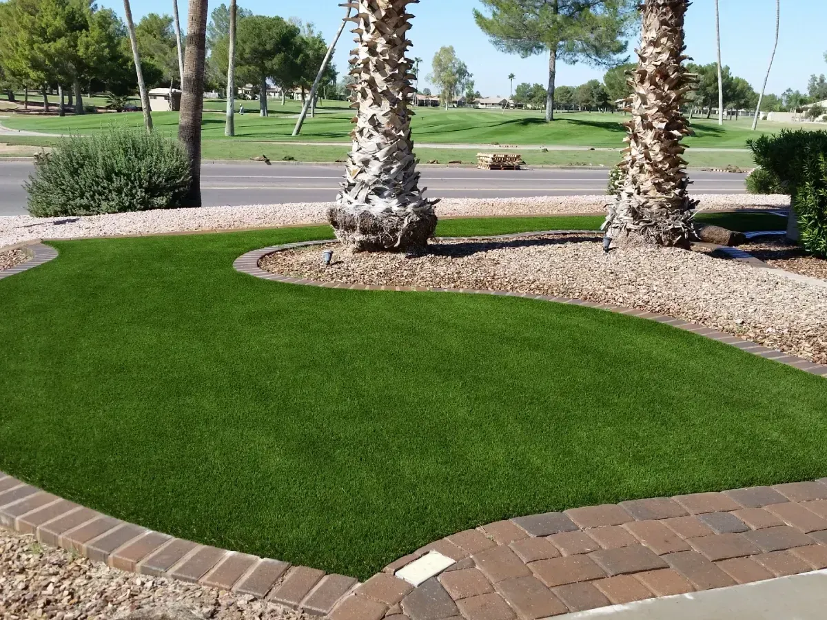 Curved green lawn bordered by brick path and palm trees in a sunny park
