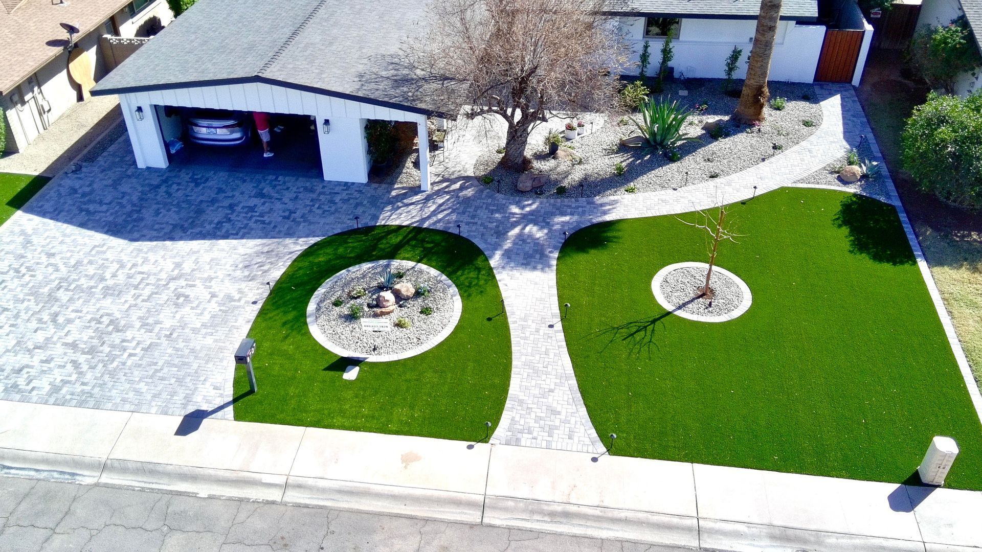 Aerial view of a house with a driveway and two landscaped front yards, each with a circular stone garden.