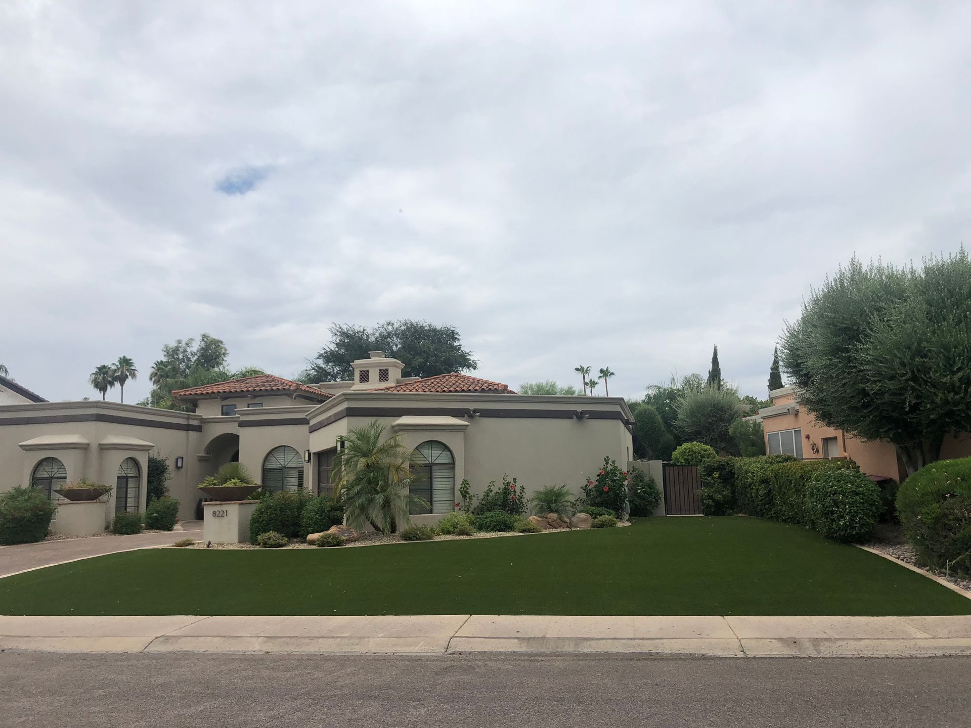 Suburban stucco house with manicured lawn and cloudy sky