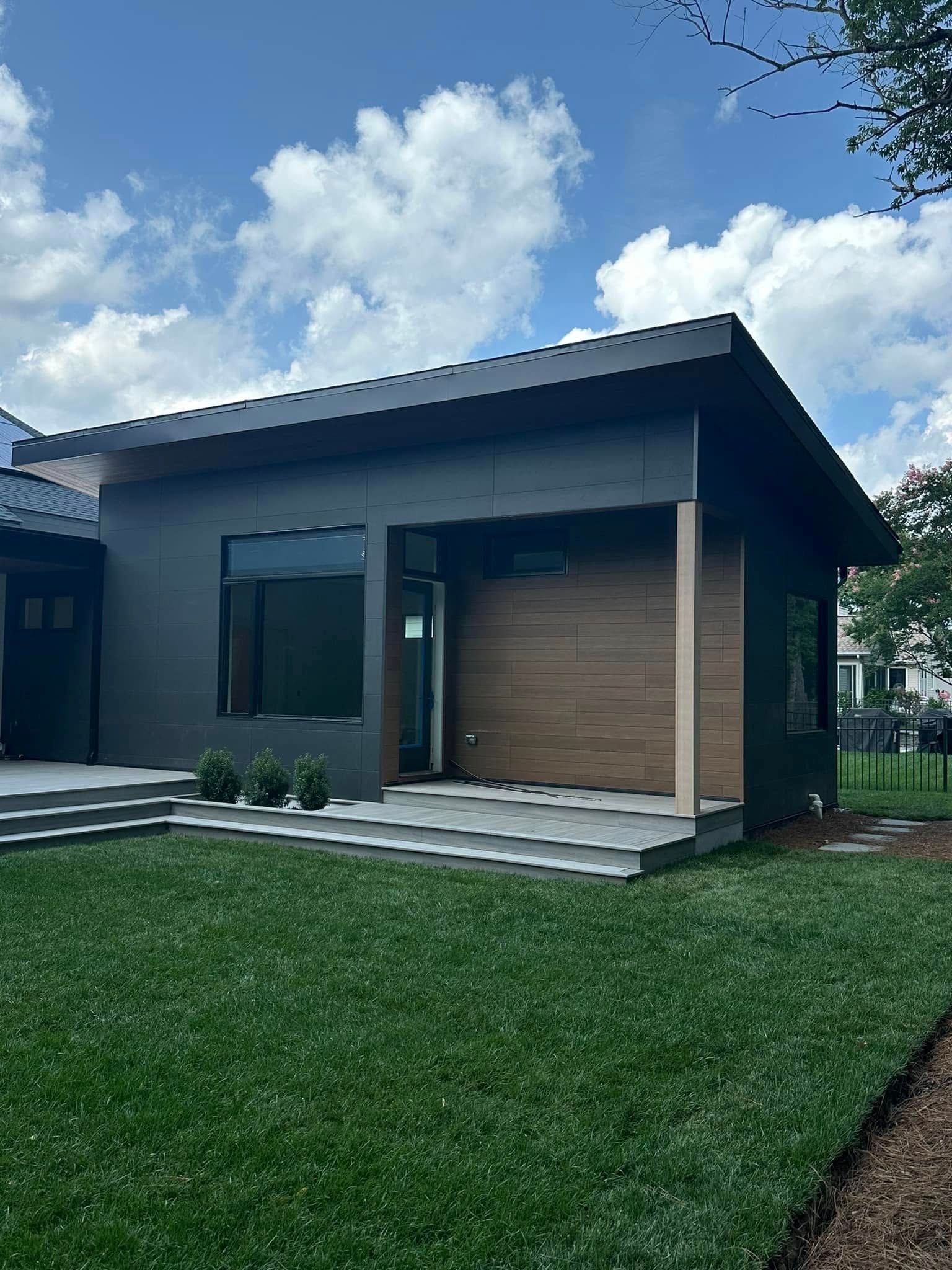 A small house with a large garage door is sitting on top of a lush green lawn.