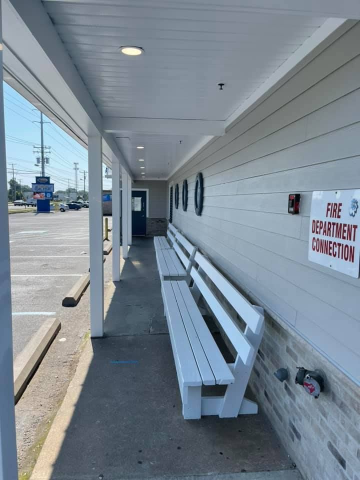 A white bench sits under a covered walkway next to a sign that says fire department connection
