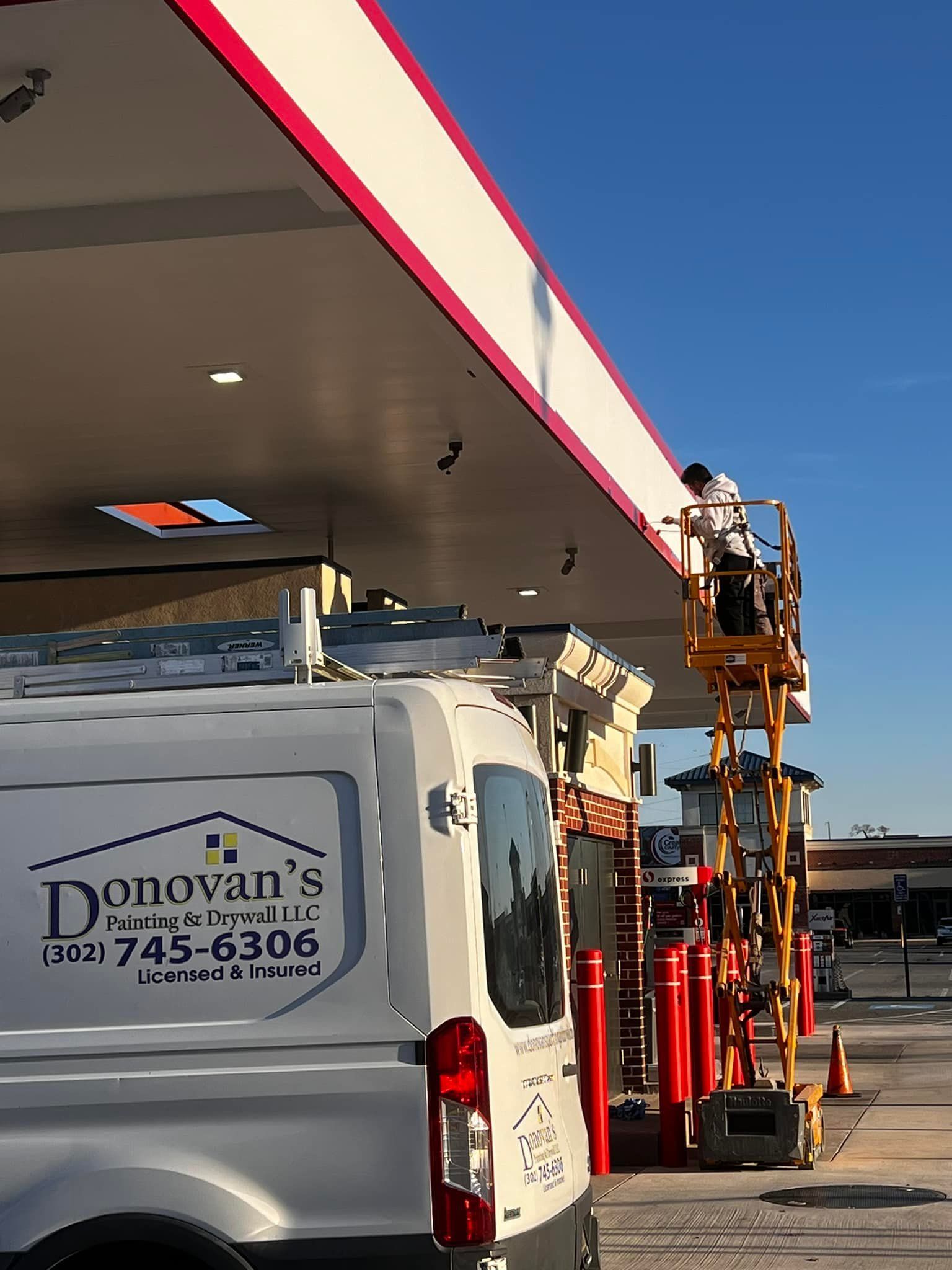 A white van is parked in front of a gas station.