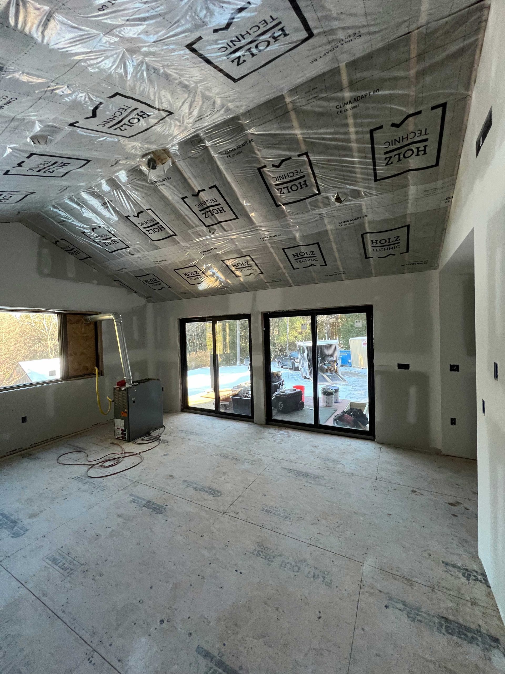 Interior of a room under construction, with insulated ceiling, drywall walls, and sliding glass doors.