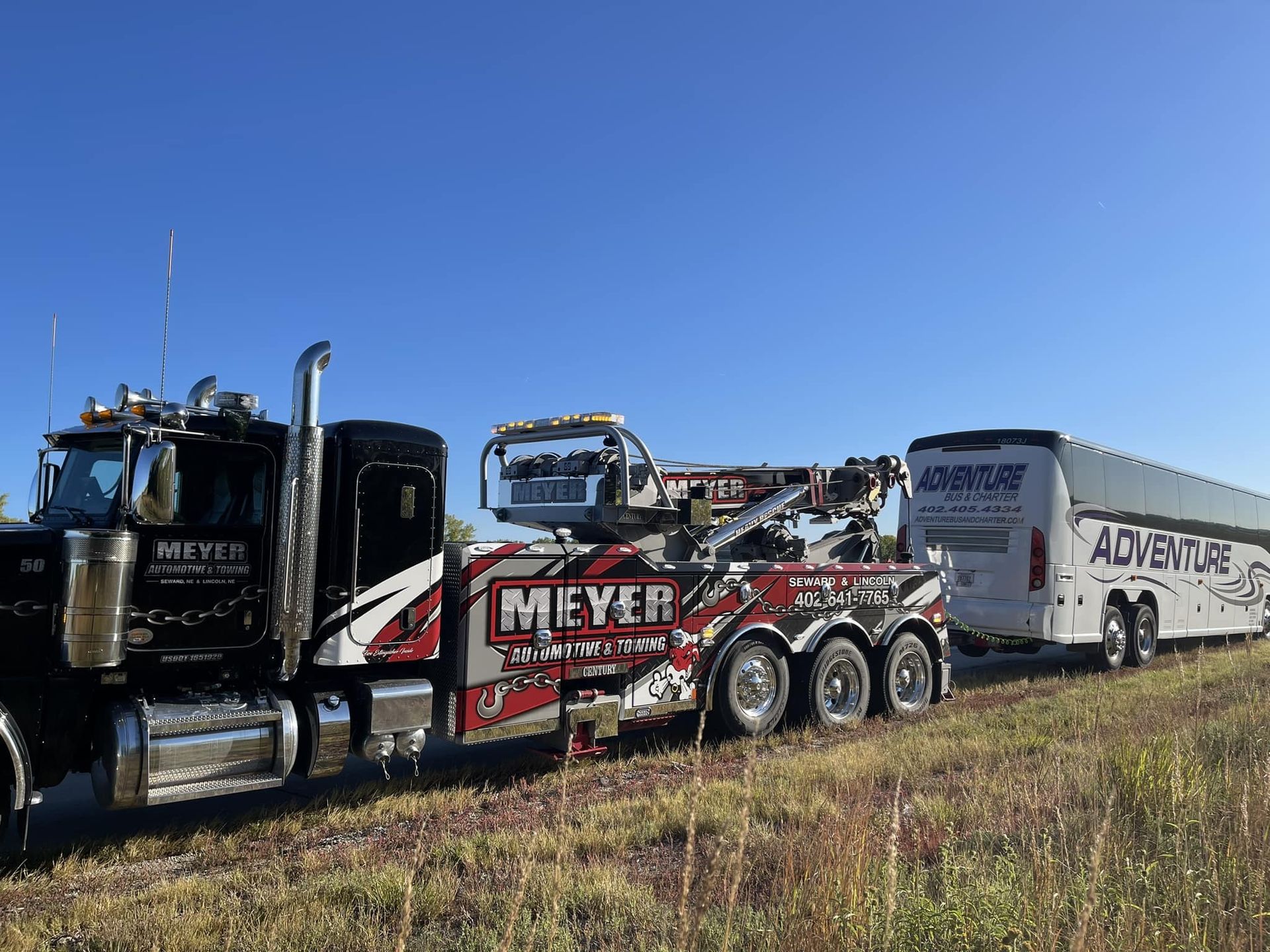 A tow truck is towing a bus in a field