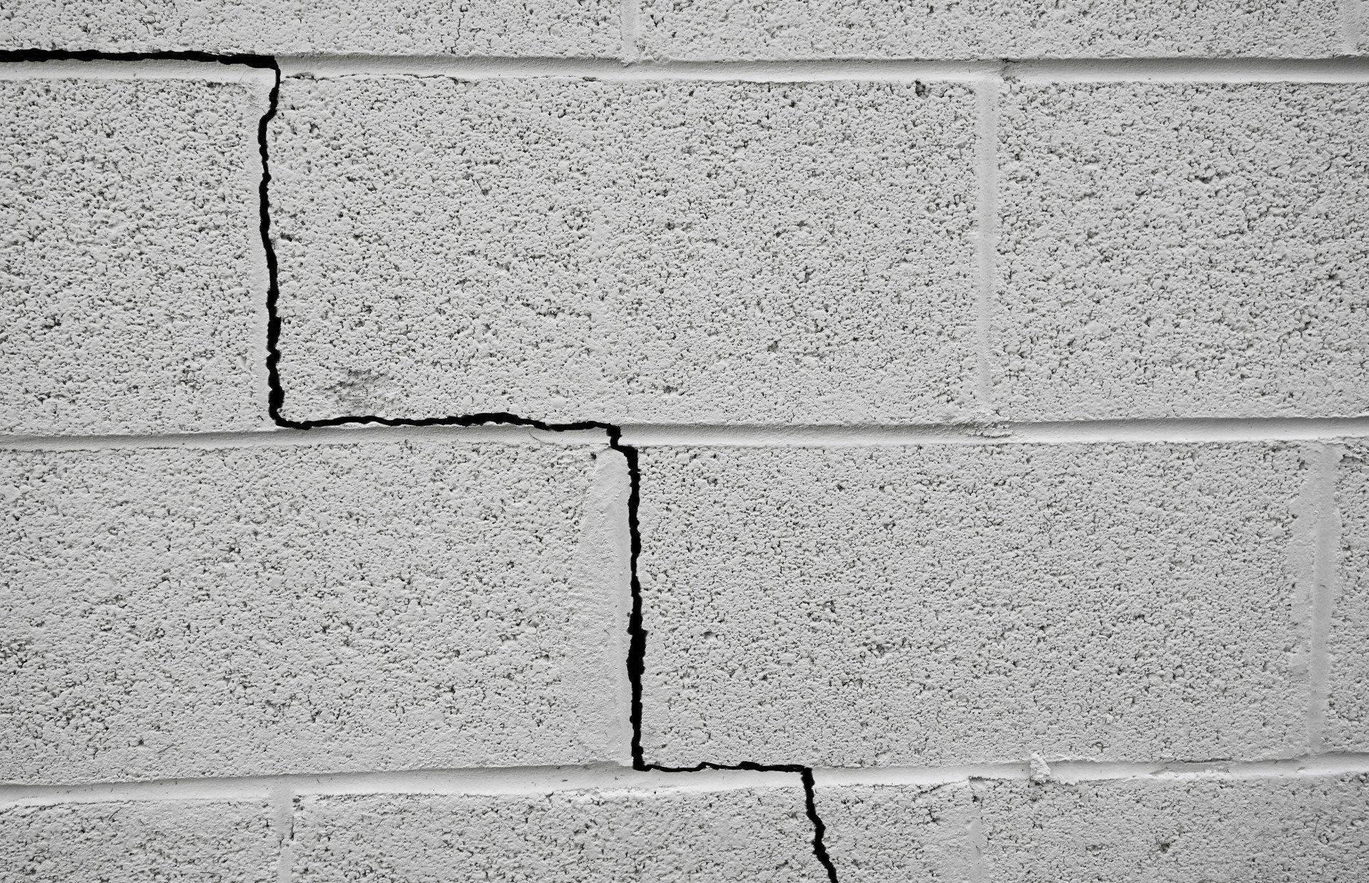 Gray cinder block wall with a staggered vertical crack running through the center