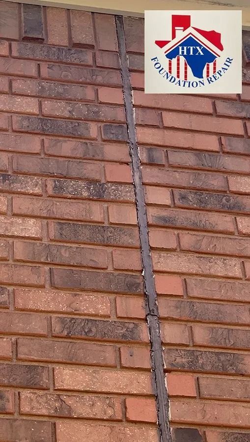 Brick wall with a Hilton logo sign mounted near the top and a vertical cable running down the center.