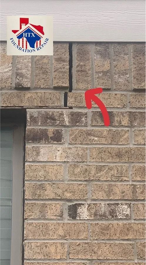 Brick wall with a red arrow pointing to a vertical crack near the top
