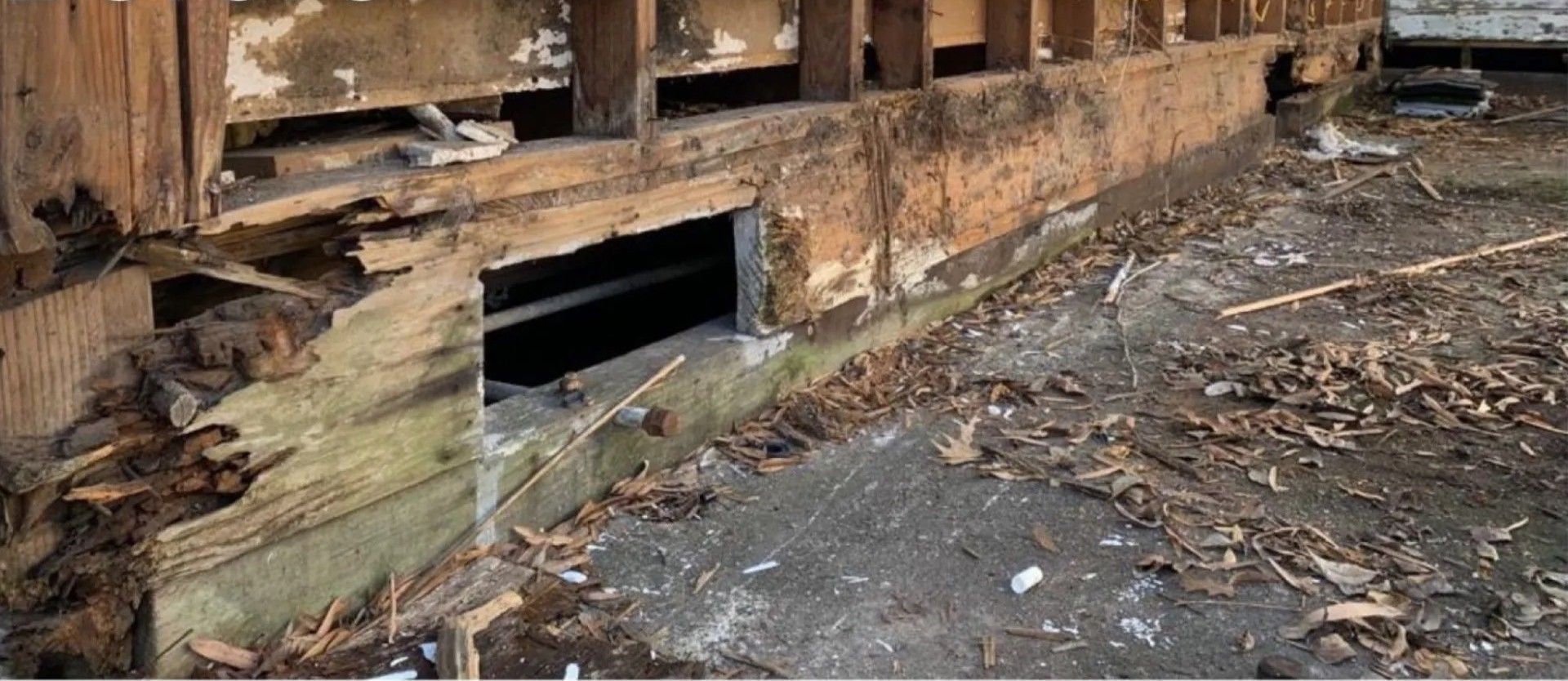 Charred building interior with a blackened doorway and debris-strewn floor after fire damage