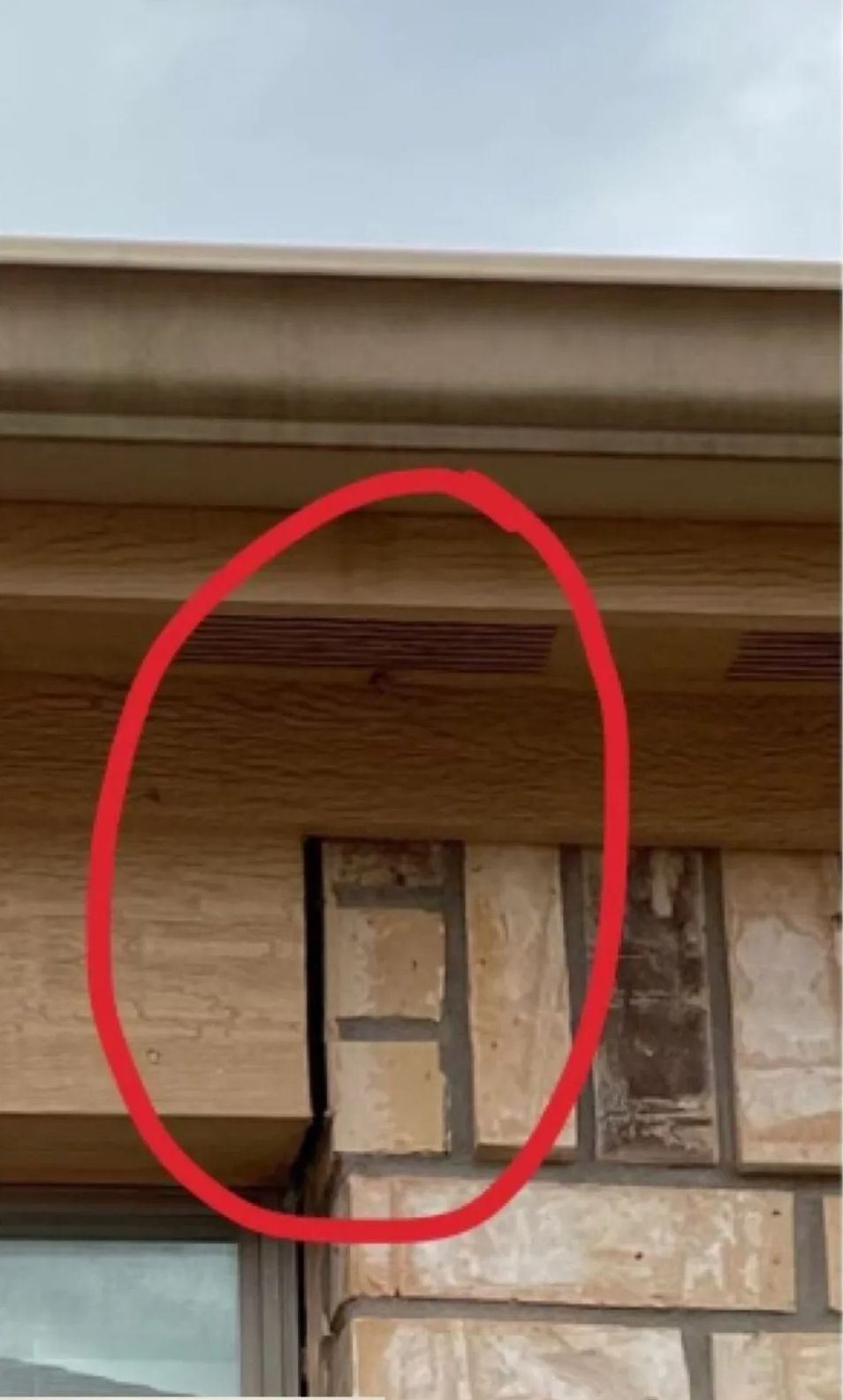 Red circle highlighting a small brick section beneath a roof eave on an exterior wall.