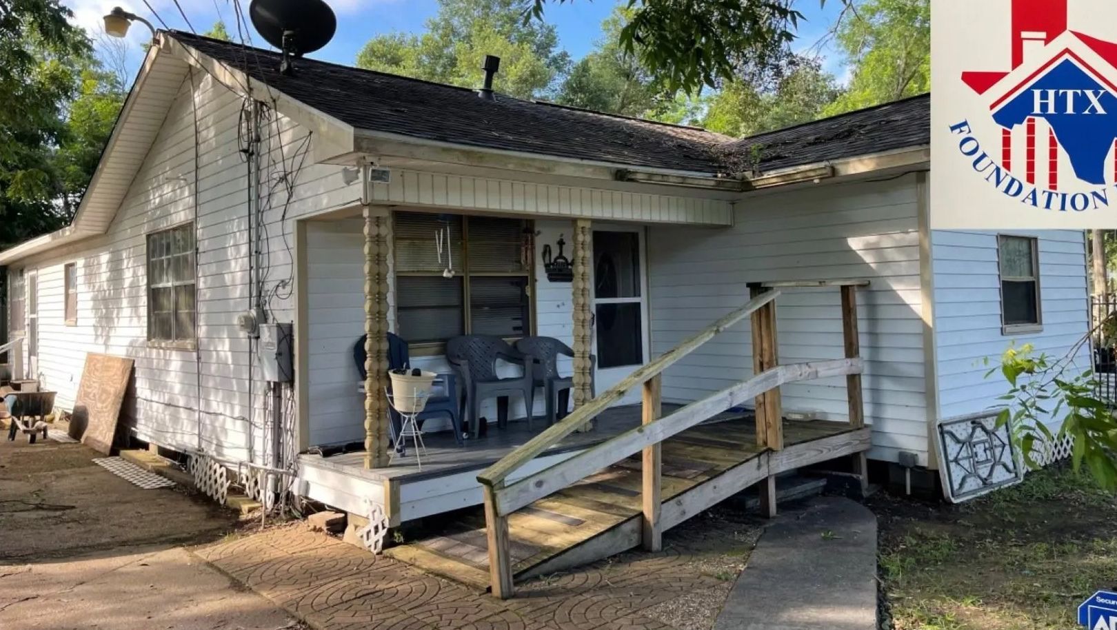 White house with front porch ramp and satellite dish under trees, with a Texas logo overlay in the corner