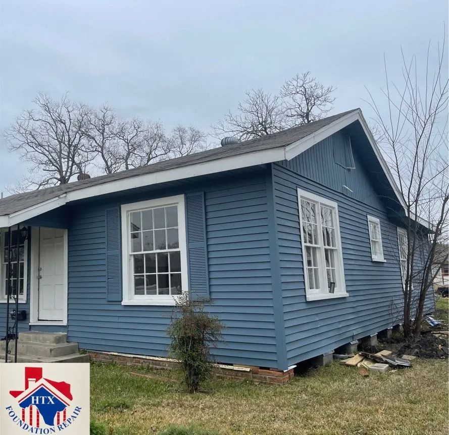 Blue house with white trim and a white front door, seen from the side in a grassy yard on an overcast day