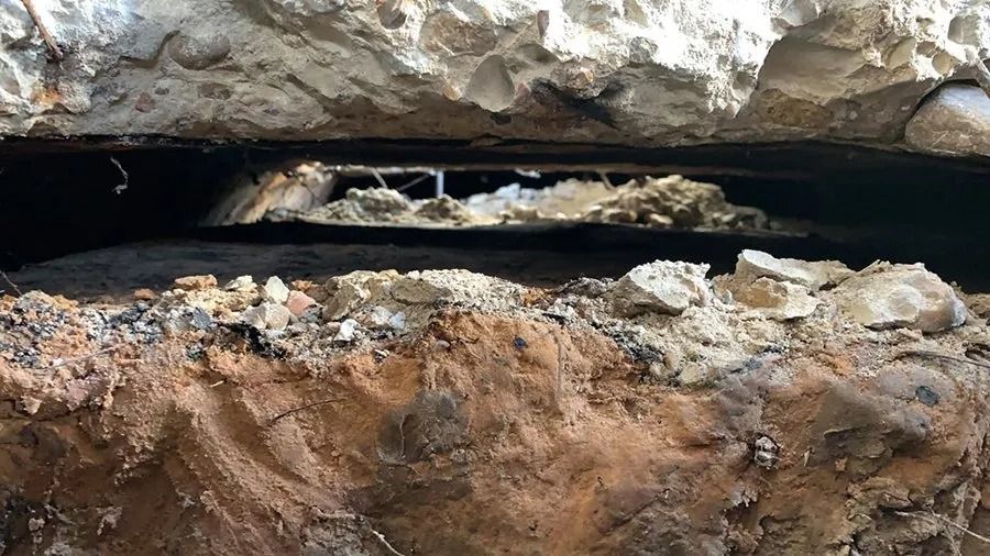 Close-up of a rocky crevice with dark water running through layered brown and gray stone.