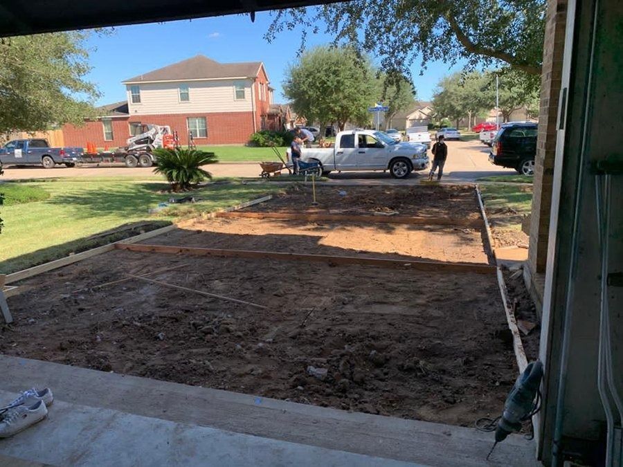 Front yard with a large dirt patch, a white pickup truck, and two workers by a suburban house.