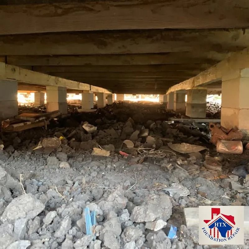 Rubble and debris under a concrete overpass, with daylight visible at the far end.