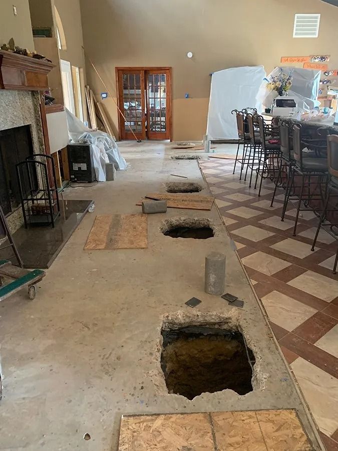 Indoor room with large holes cut in the floor, construction debris, and bar stools along the right wall.
