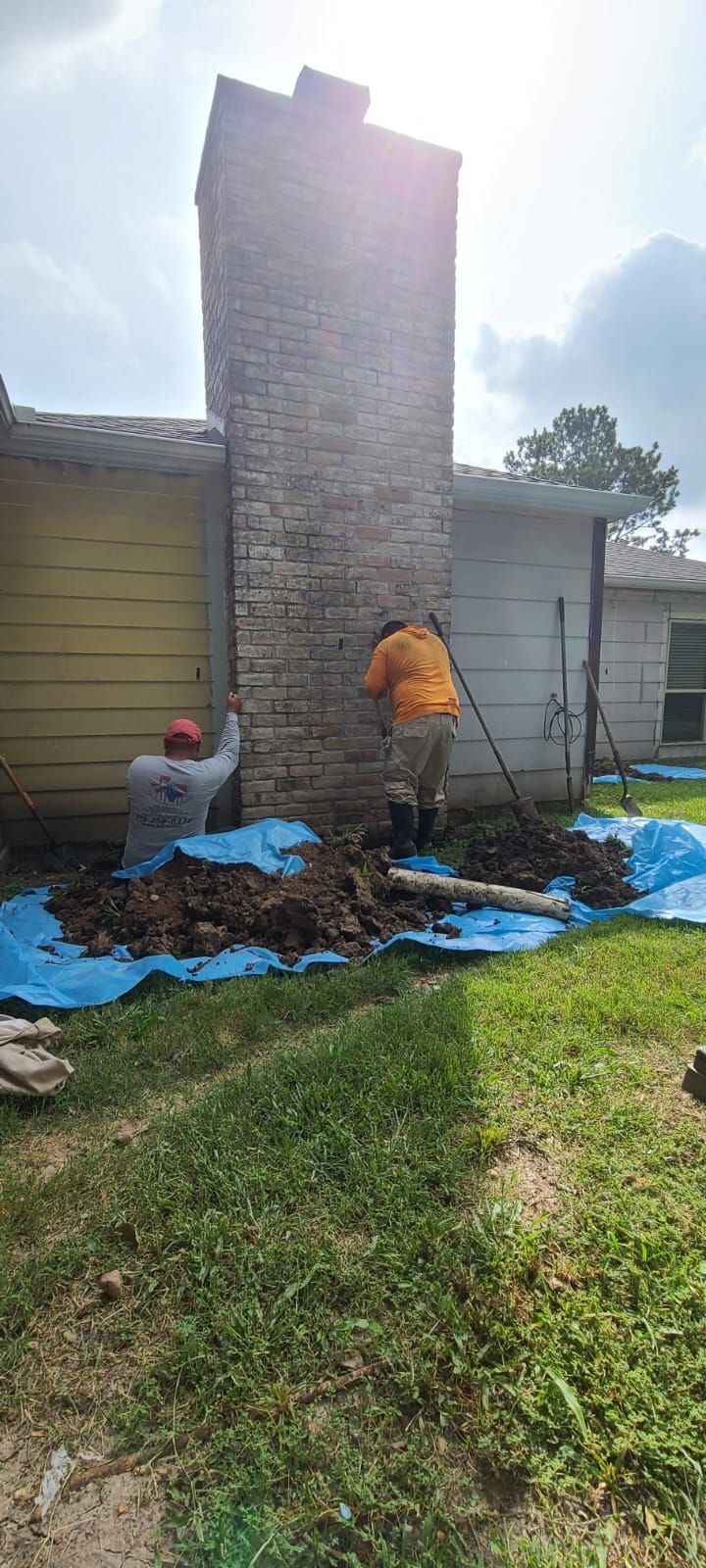 Person in orange shirt working on a damaged brick chimney outside a house with debris on the ground