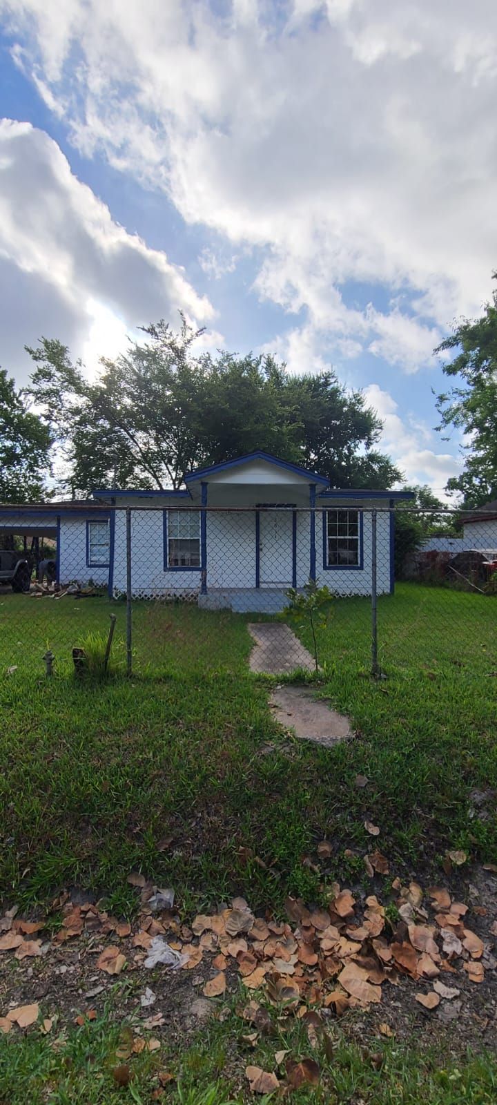 Small white house with a front porch and walkway, set in a grassy yard under a cloudy sky