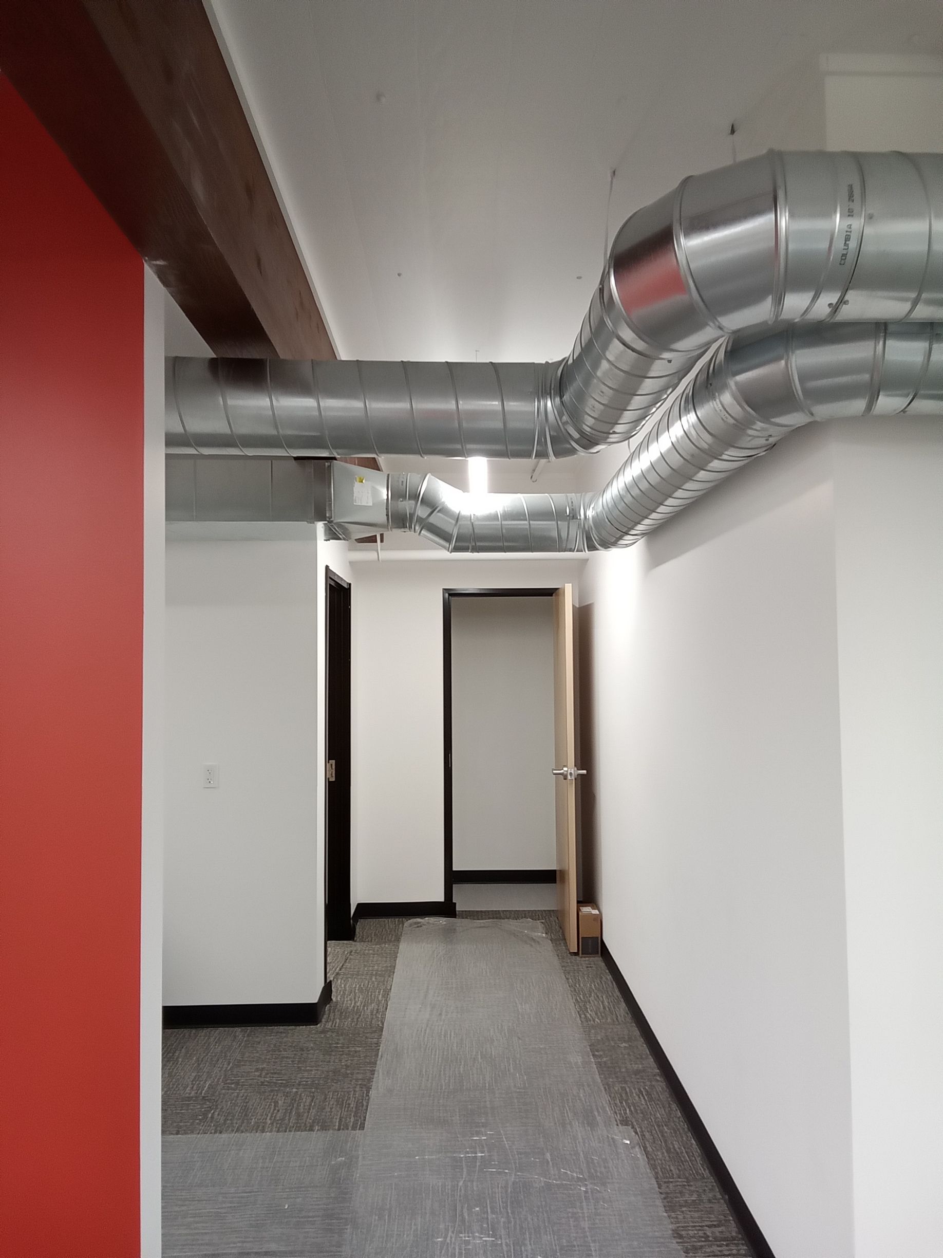 A hallway with a red wall and a lot of pipes