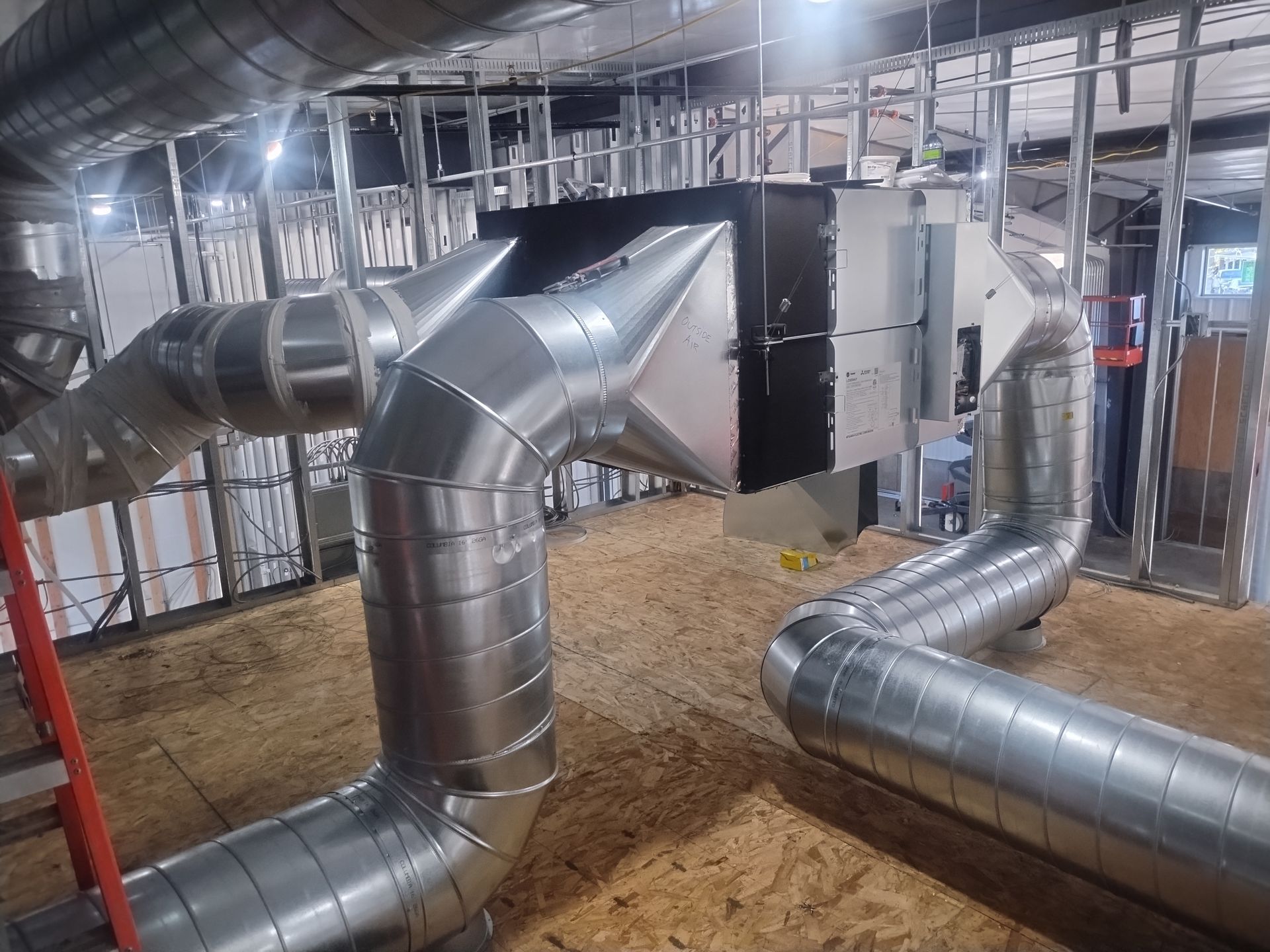 A room with a lot of pipes and a ladder in it