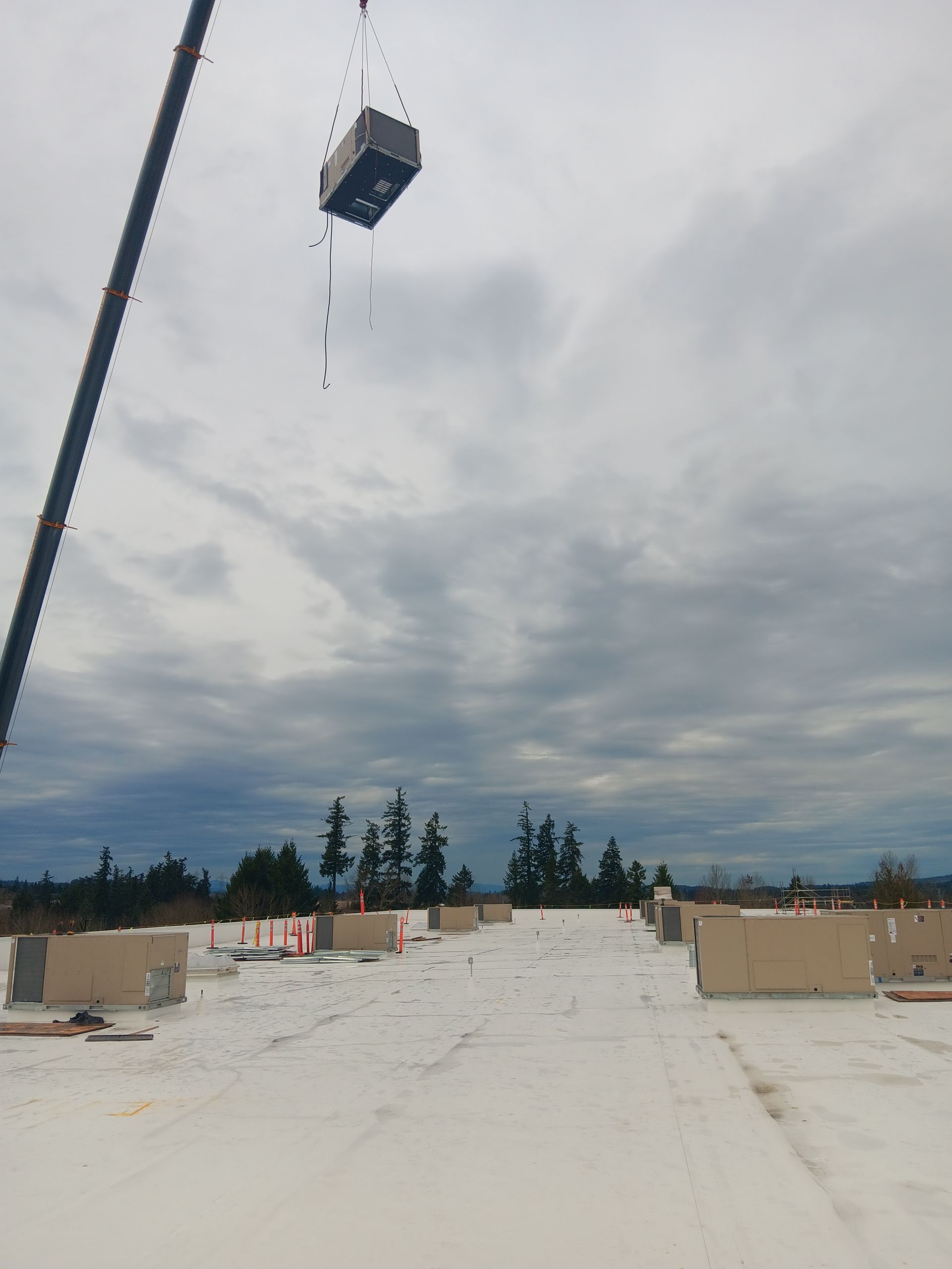 A crane is lifting a box from the roof of a building