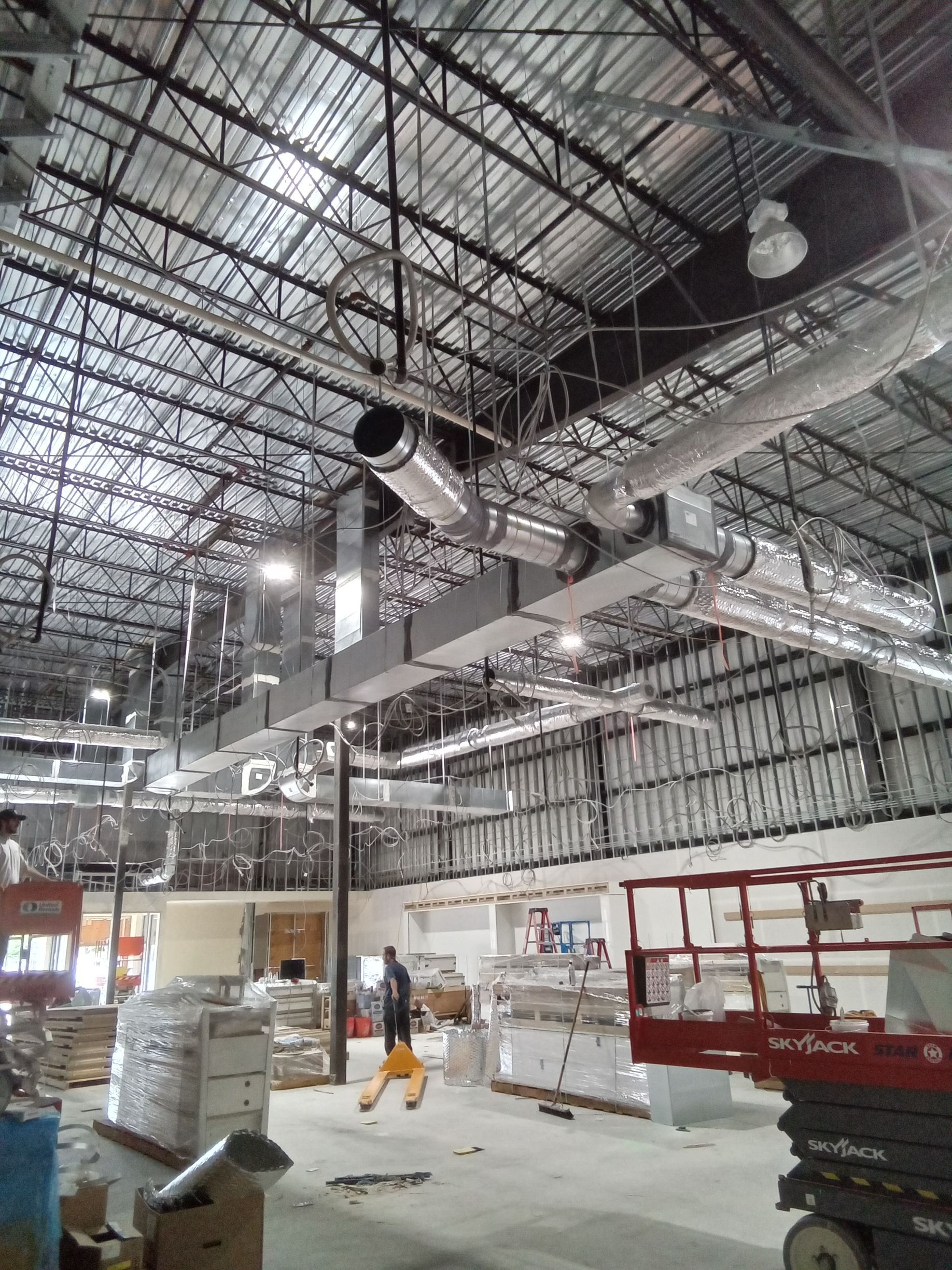 A large warehouse with a lot of pipes hanging from the ceiling