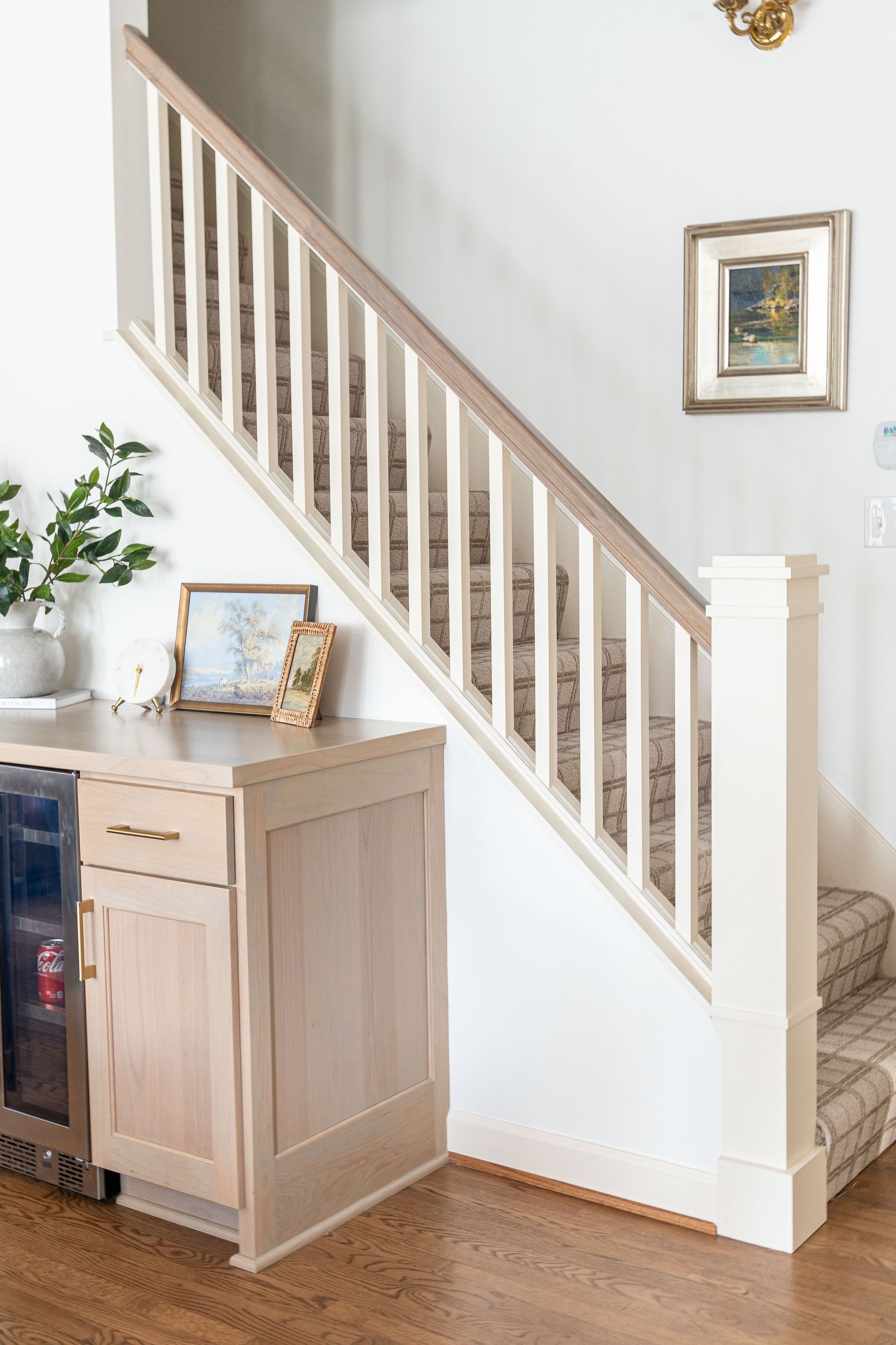 A staircase with a wooden railing and a wooden cabinet underneath it.