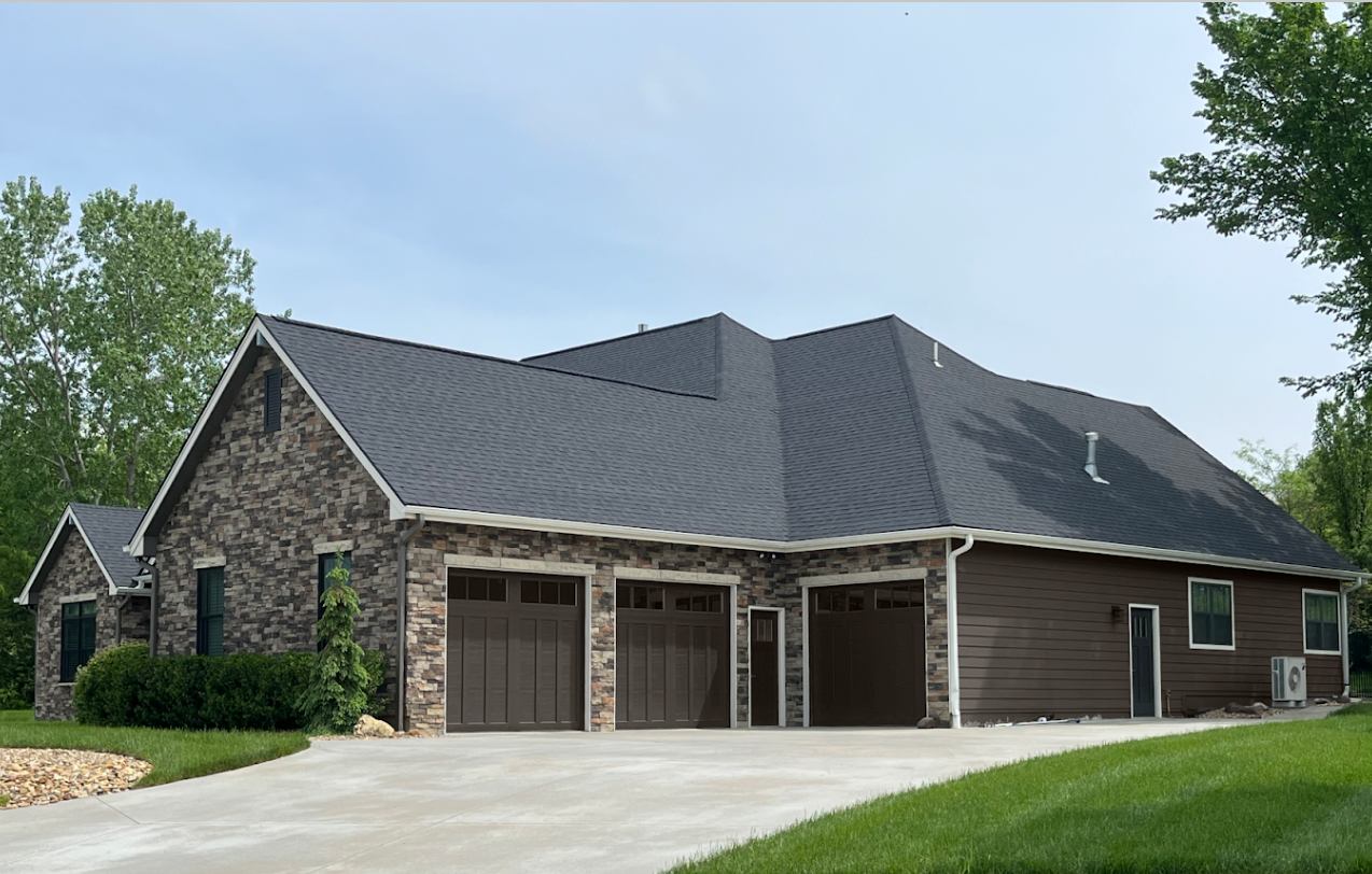 A large house with three garage doors and a driveway