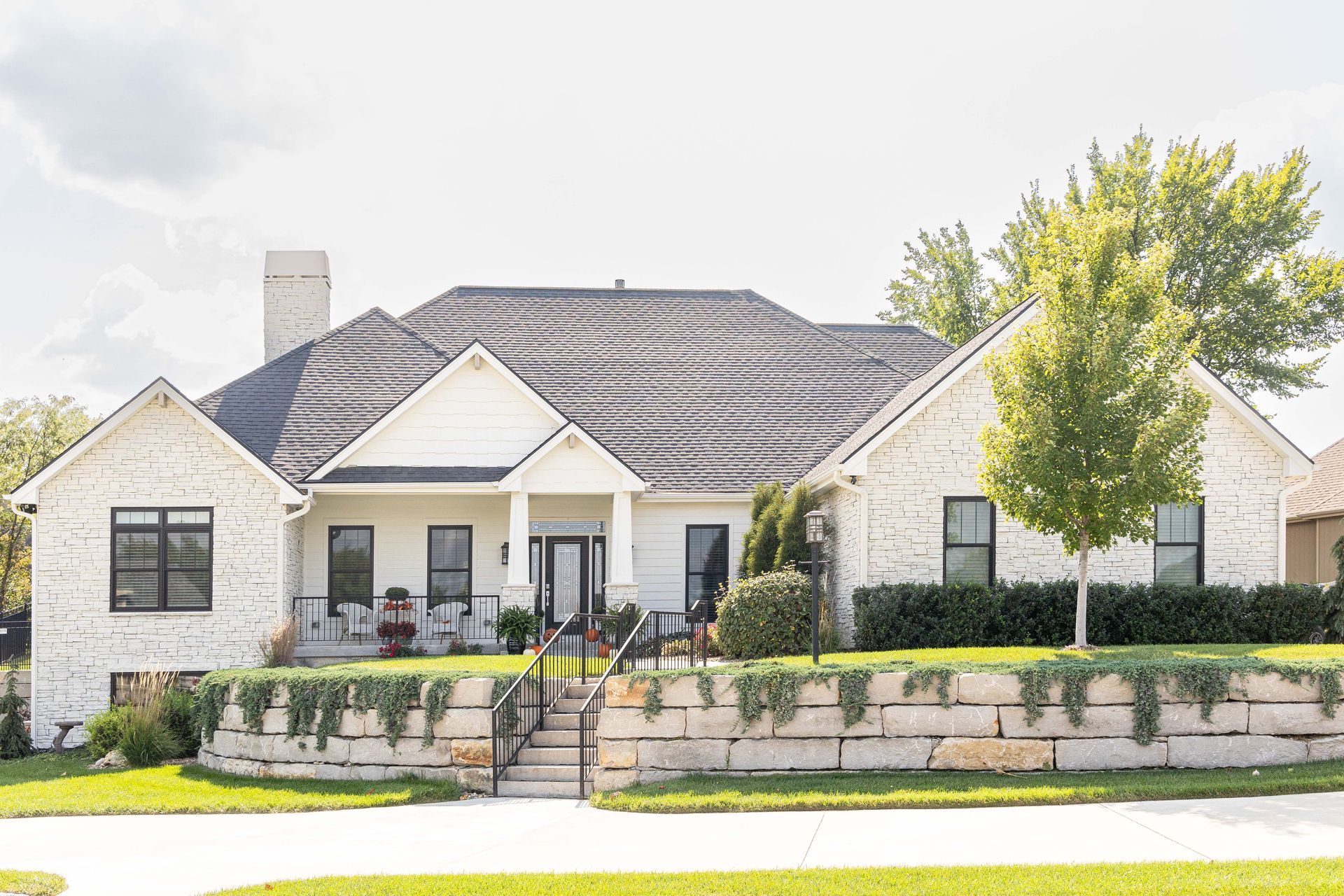A large white house with a stone wall in front of it.