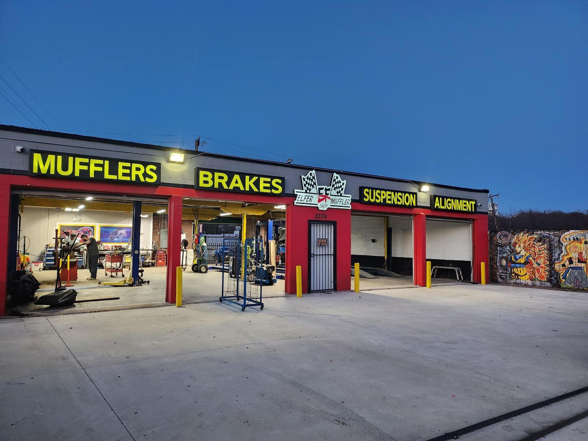 A red and yellow garage with a sign that says mufflers brakes and suspension.