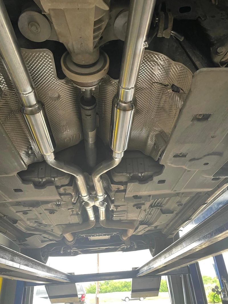 The underside of a car is shown in a garage.