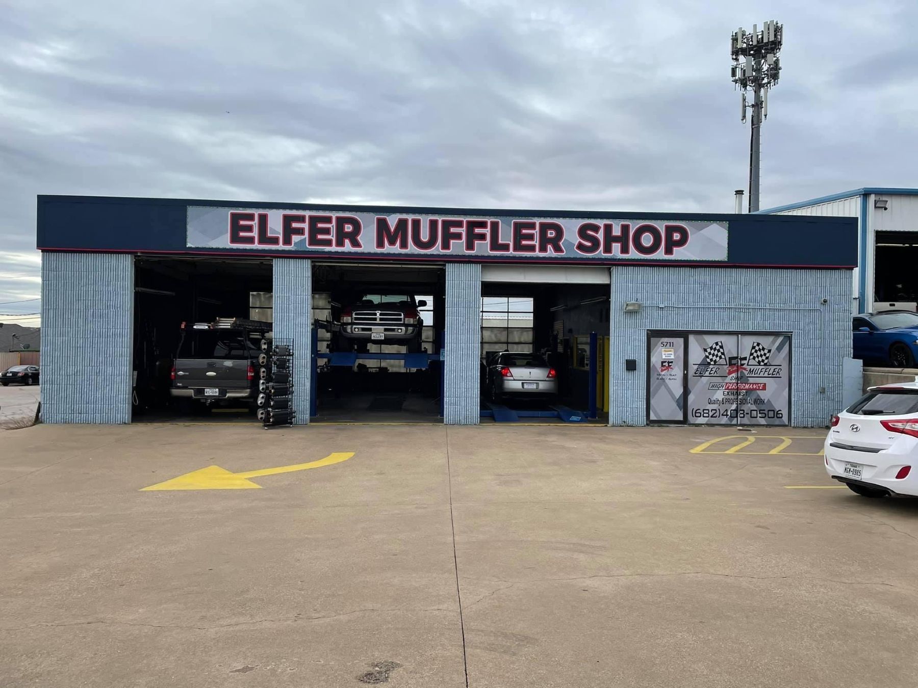 A car is parked in front of a building that says elfer muffler shop.