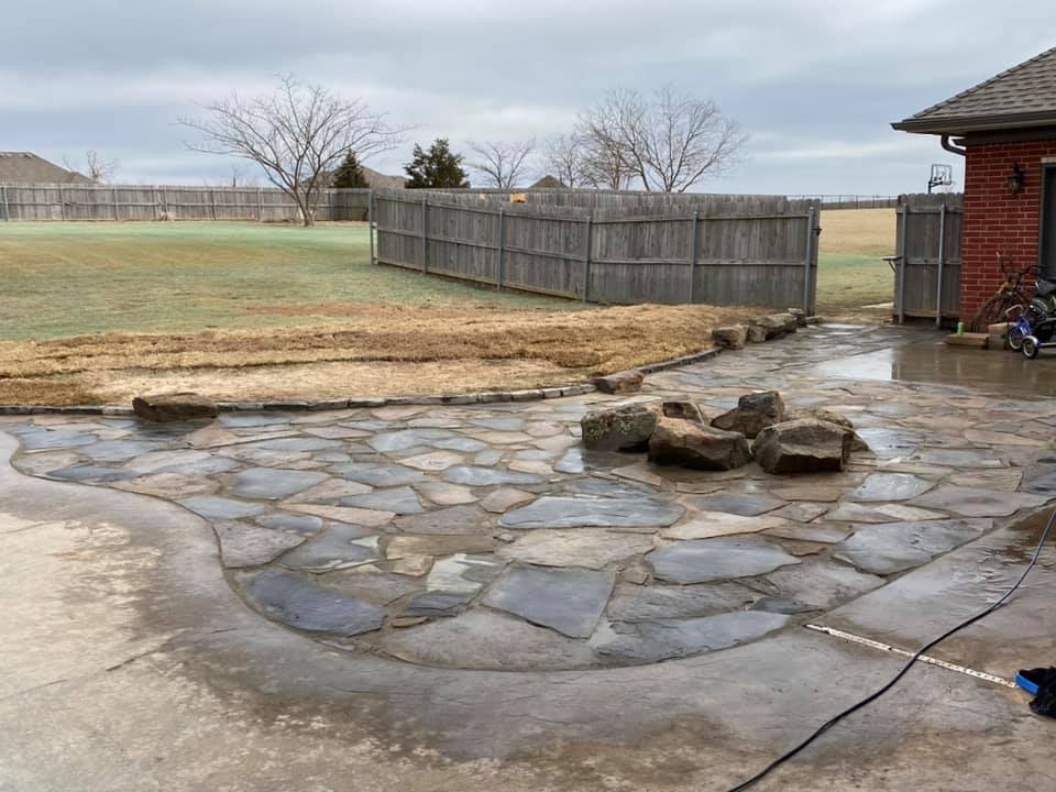 A stone patio is being built in front of a brick house.