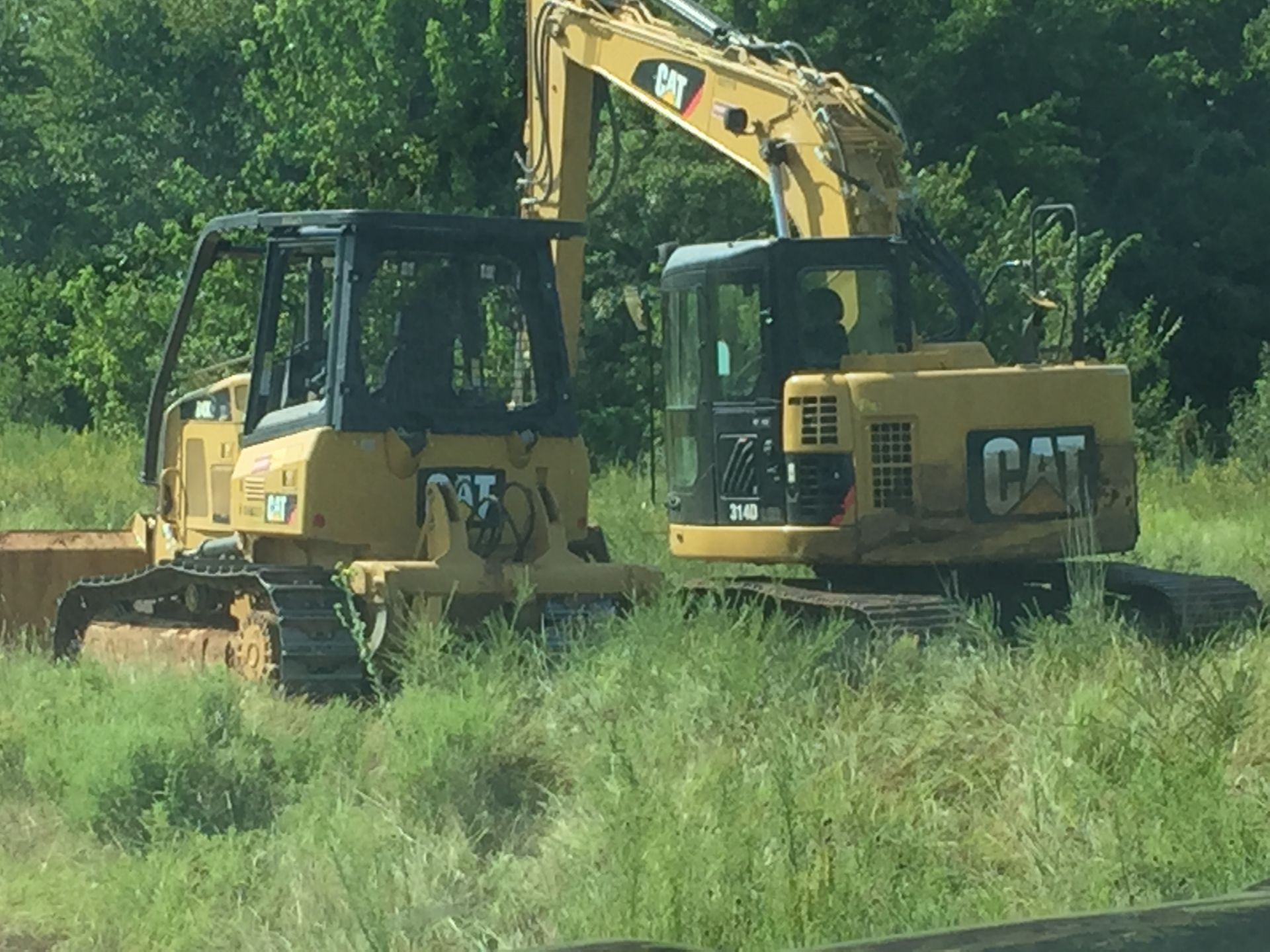 Two cat tractors are parked in a grassy field