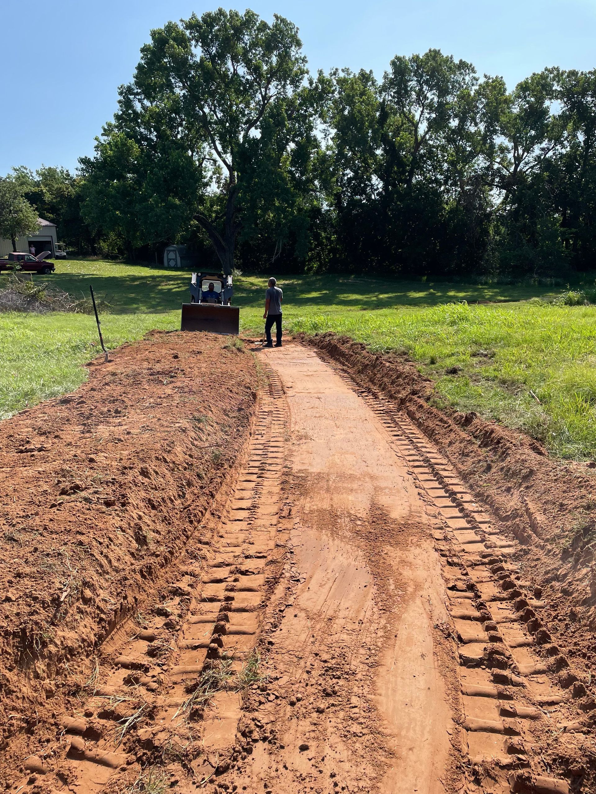 A man is standing in the middle of a dirt road.