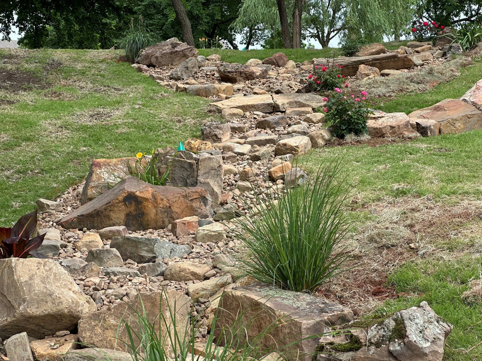 A stream of rocks runs through a lush green field.