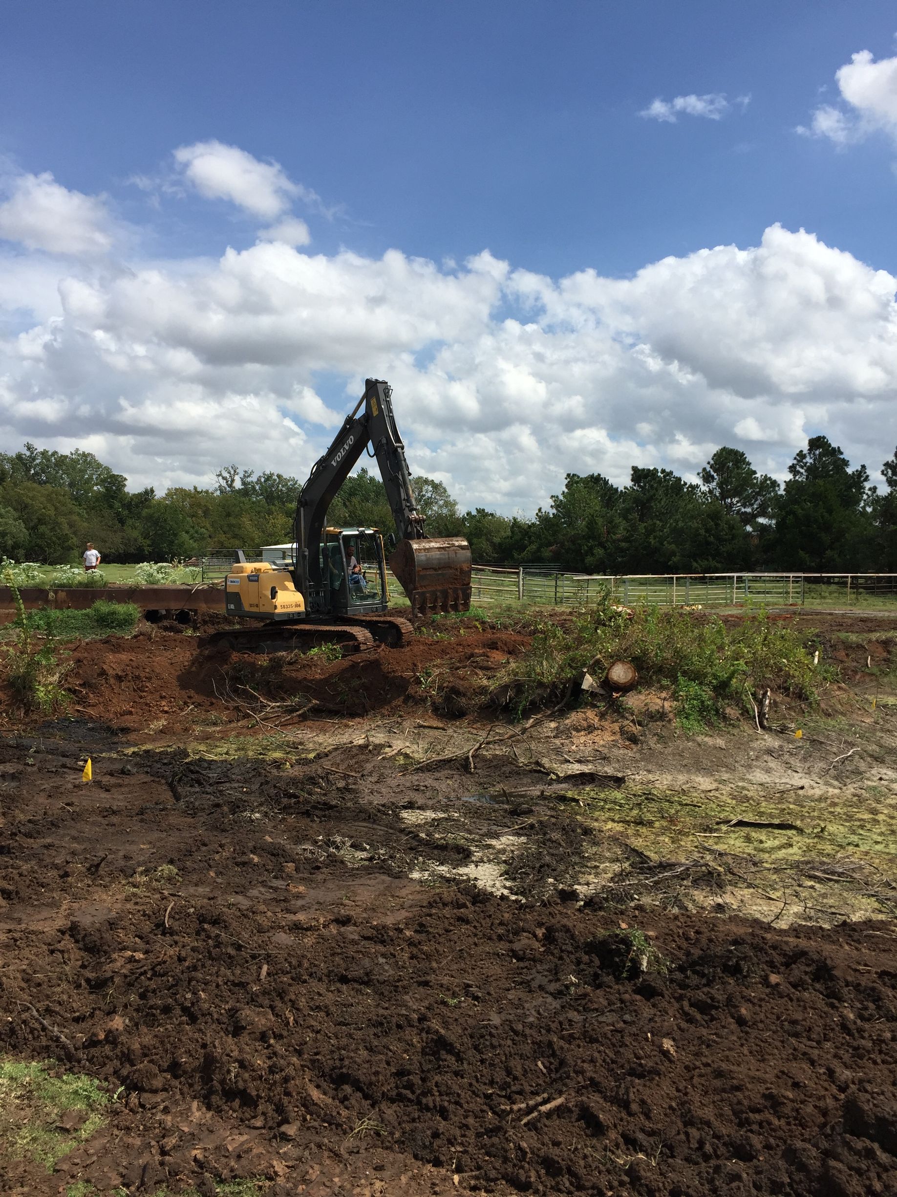 An excavator is digging a hole in the dirt in a field.