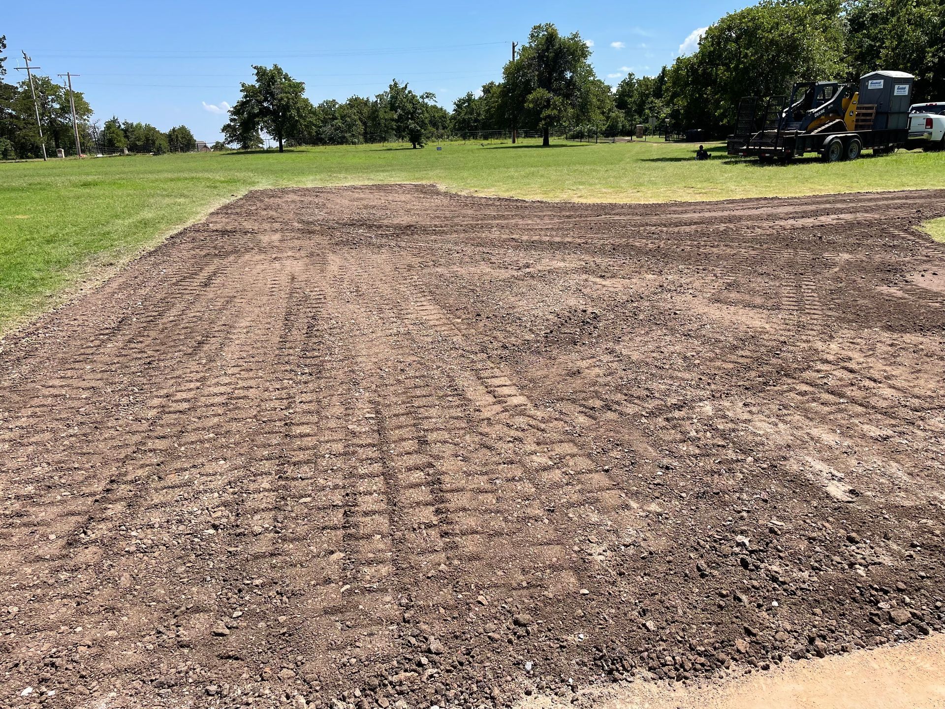 A large pile of dirt in a field with trees in the background
