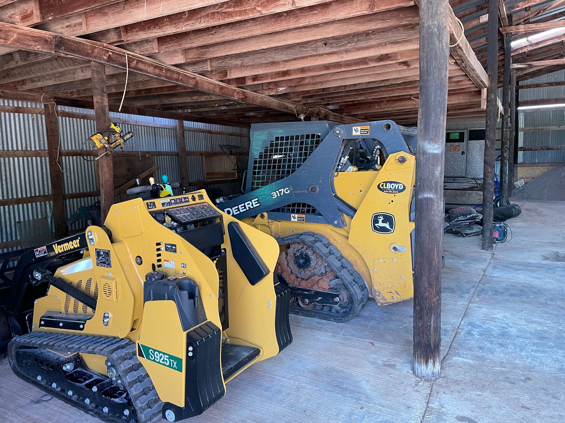 A couple of tractors are parked in a shed.