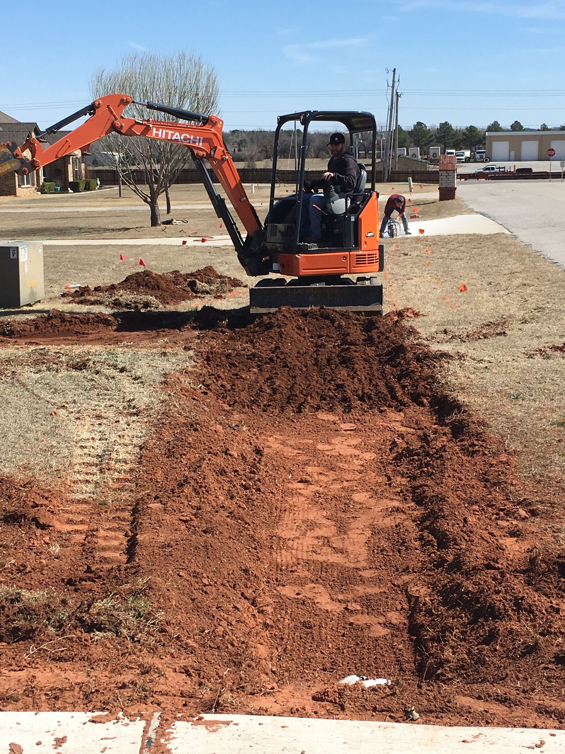 A man is driving a small excavator in a dirt field.