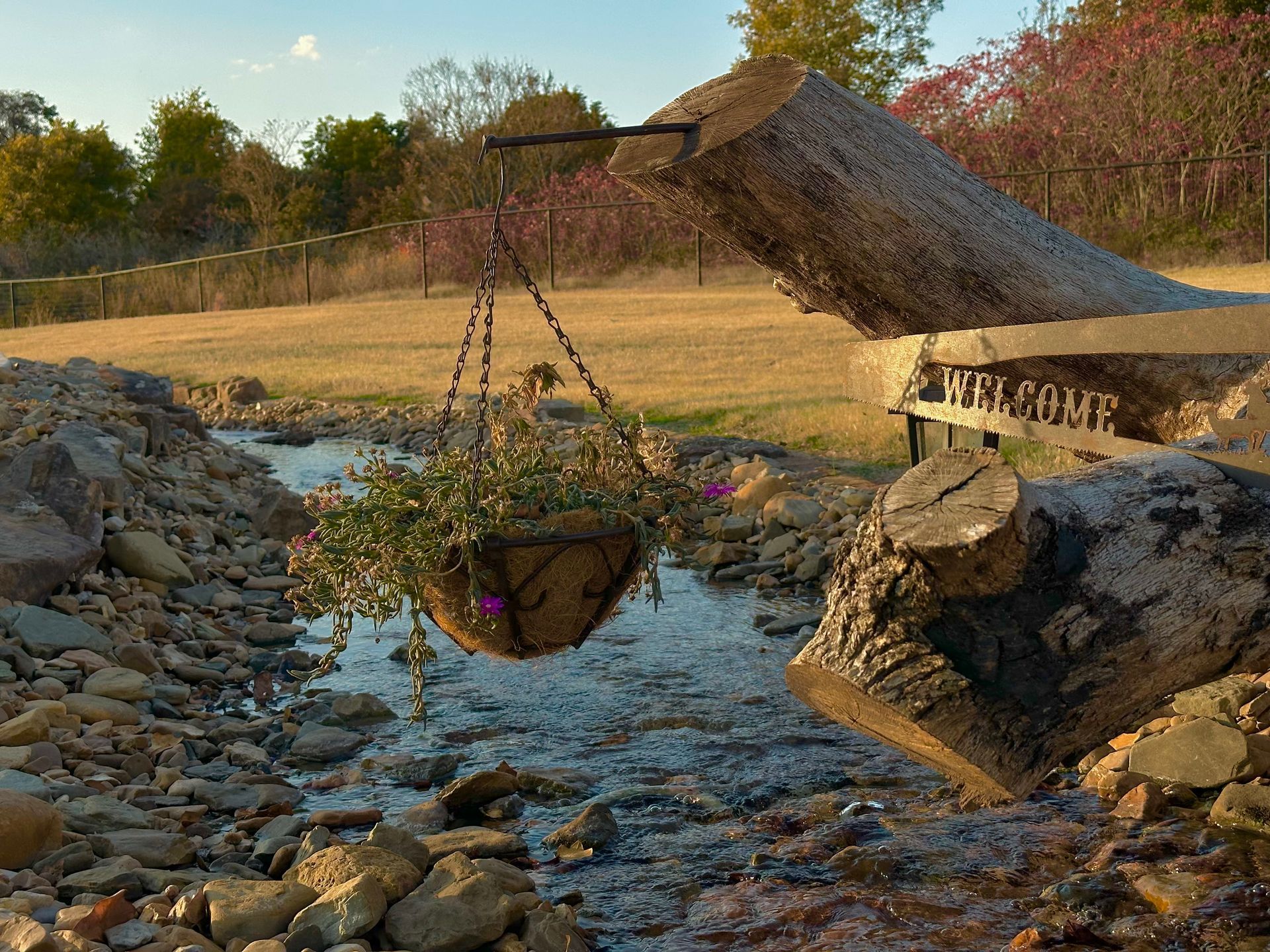 A sign that says welcome is hanging over a stream
