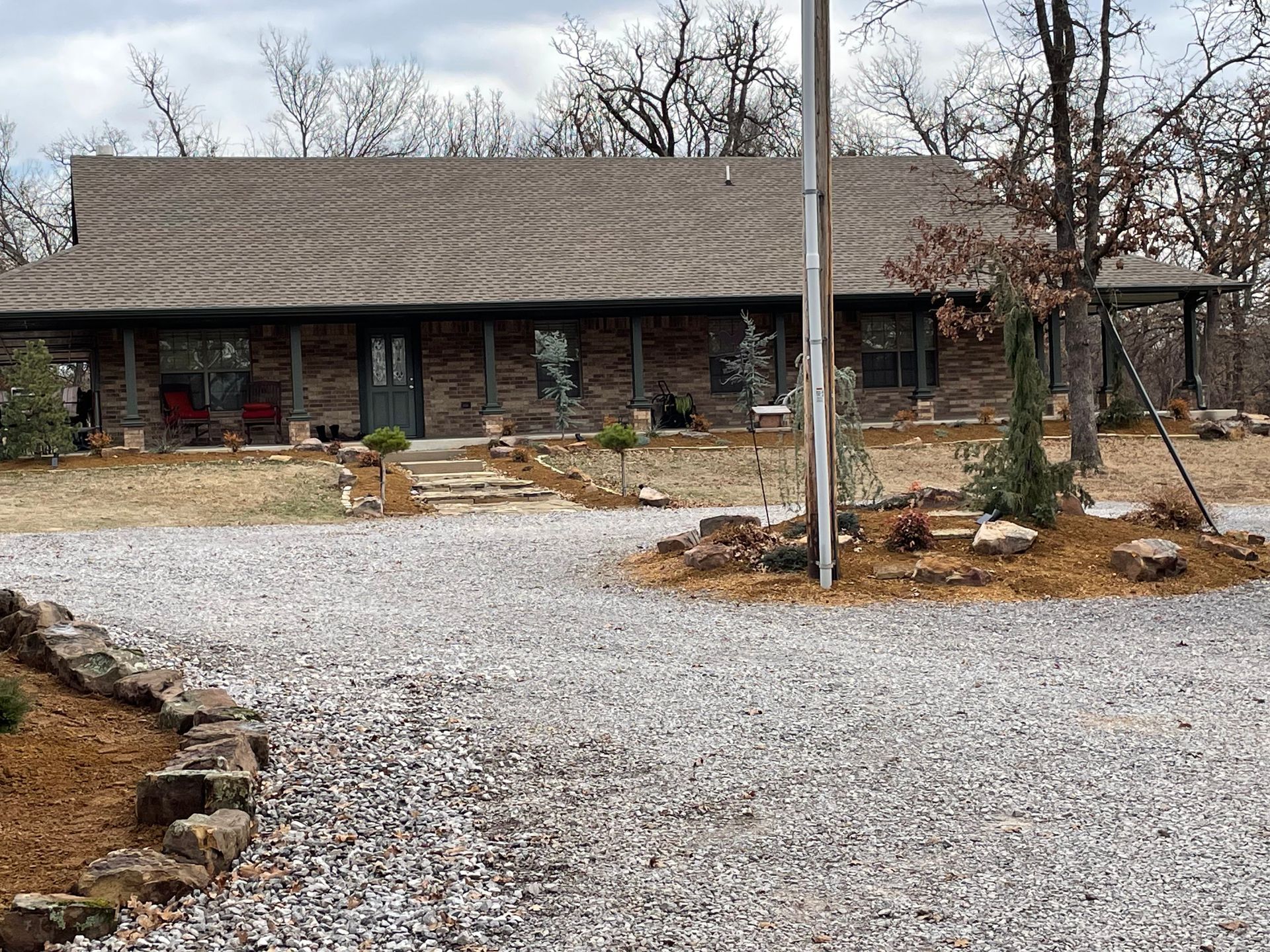 A large brick house with a gravel driveway in front of it.