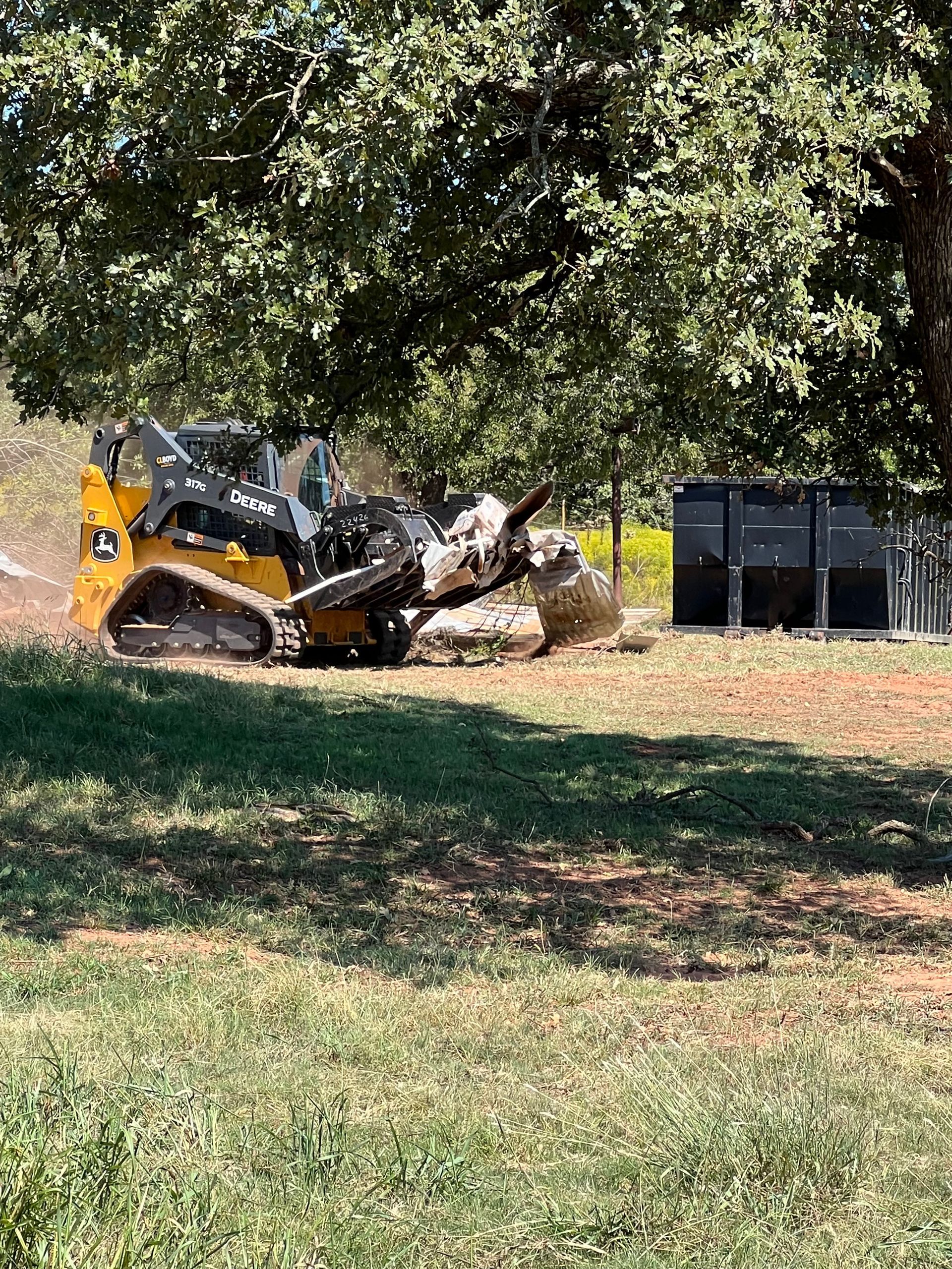 A bulldozer is cutting down a tree in a park.