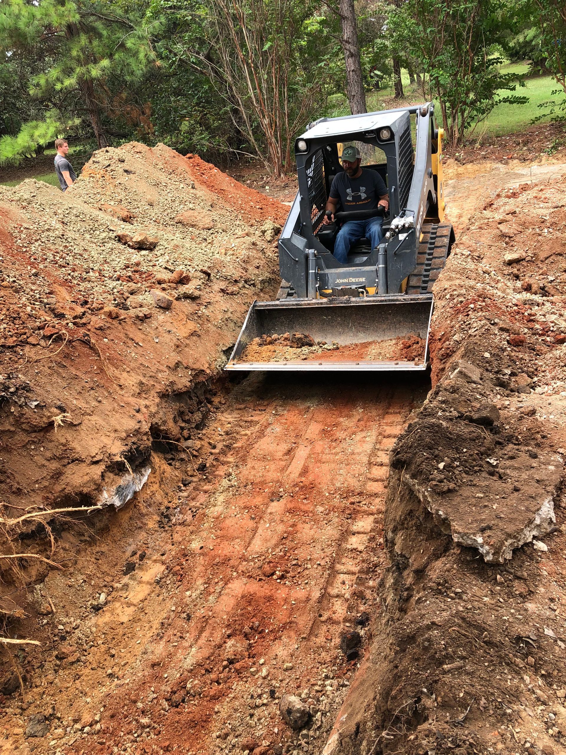 A man is driving a bulldozer on a dirt road.
