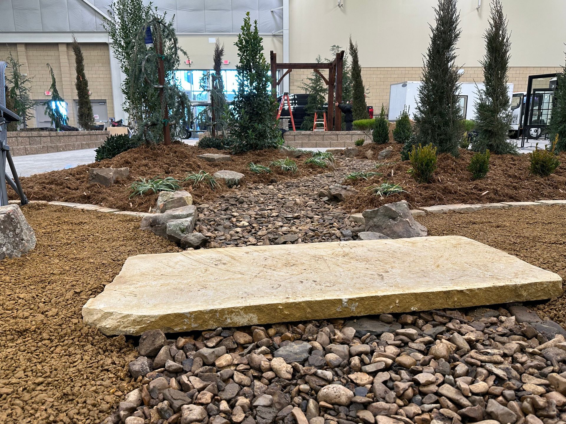 A large stone slab is sitting on top of a pile of gravel in a garden.