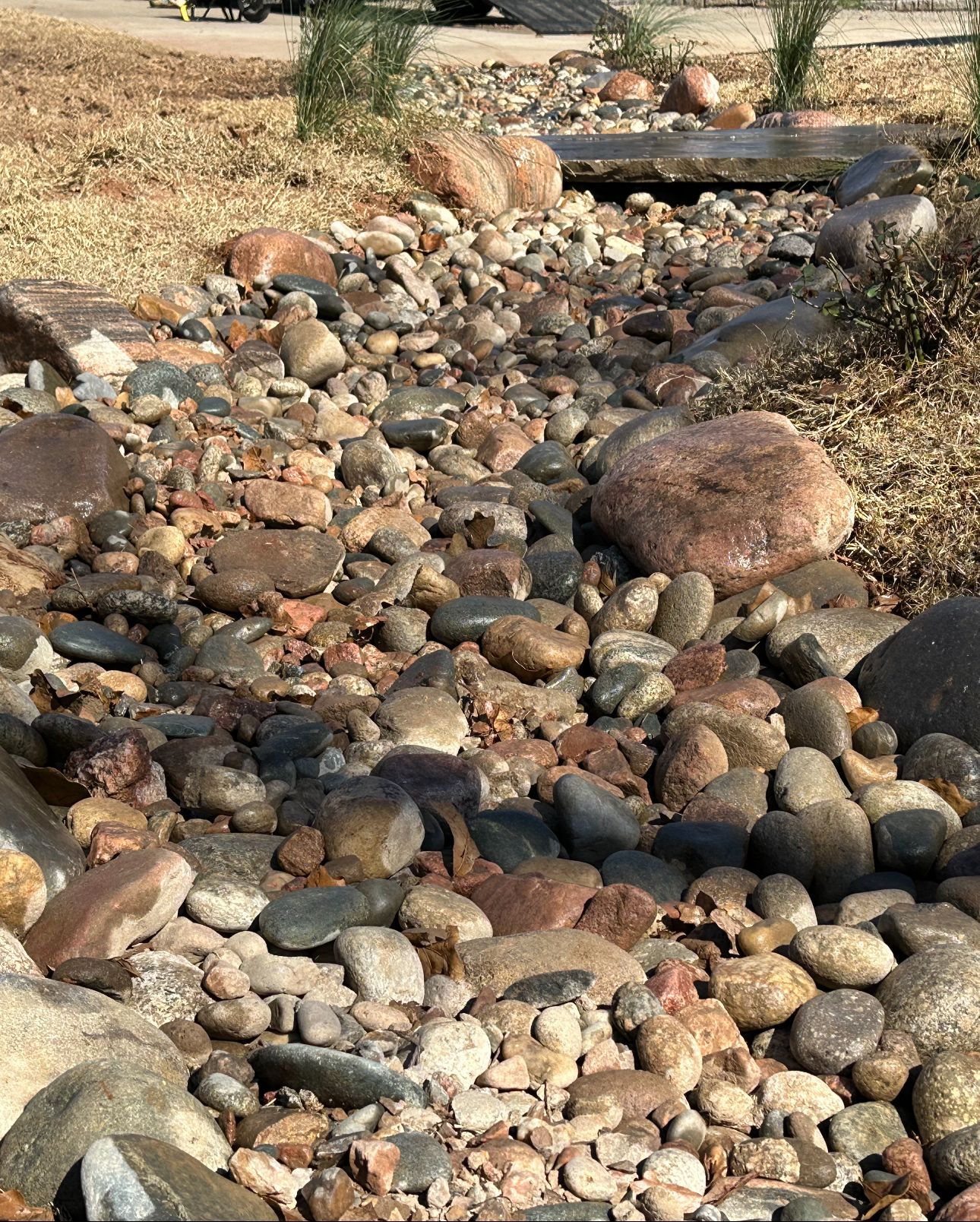 A stream of rocks runs through a lush green field.