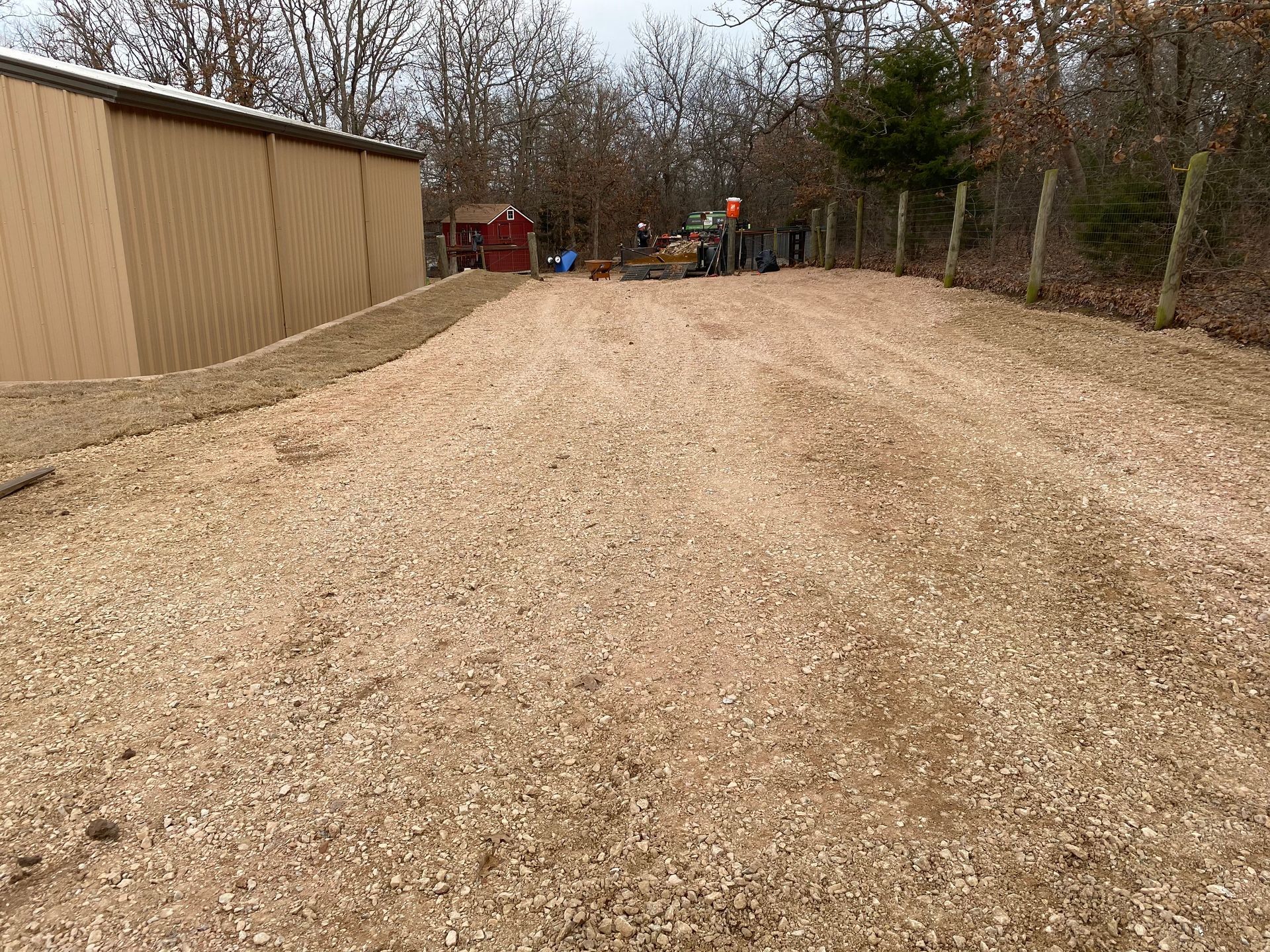 A gravel driveway leading to a shed in the woods.