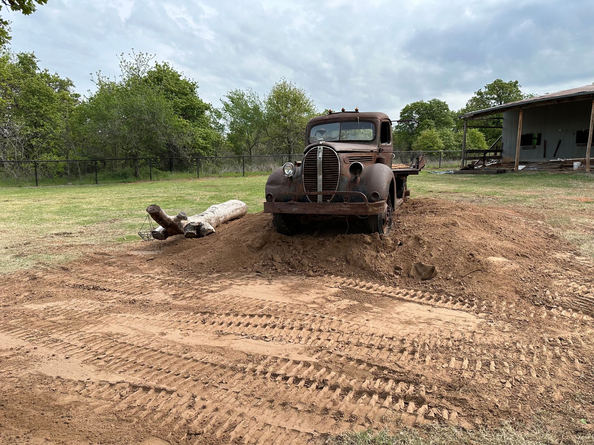 An old truck is stuck in the mud in a field.