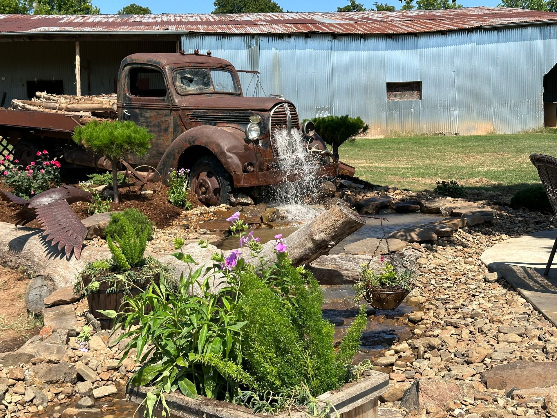An old truck is parked next to a fountain in a garden.