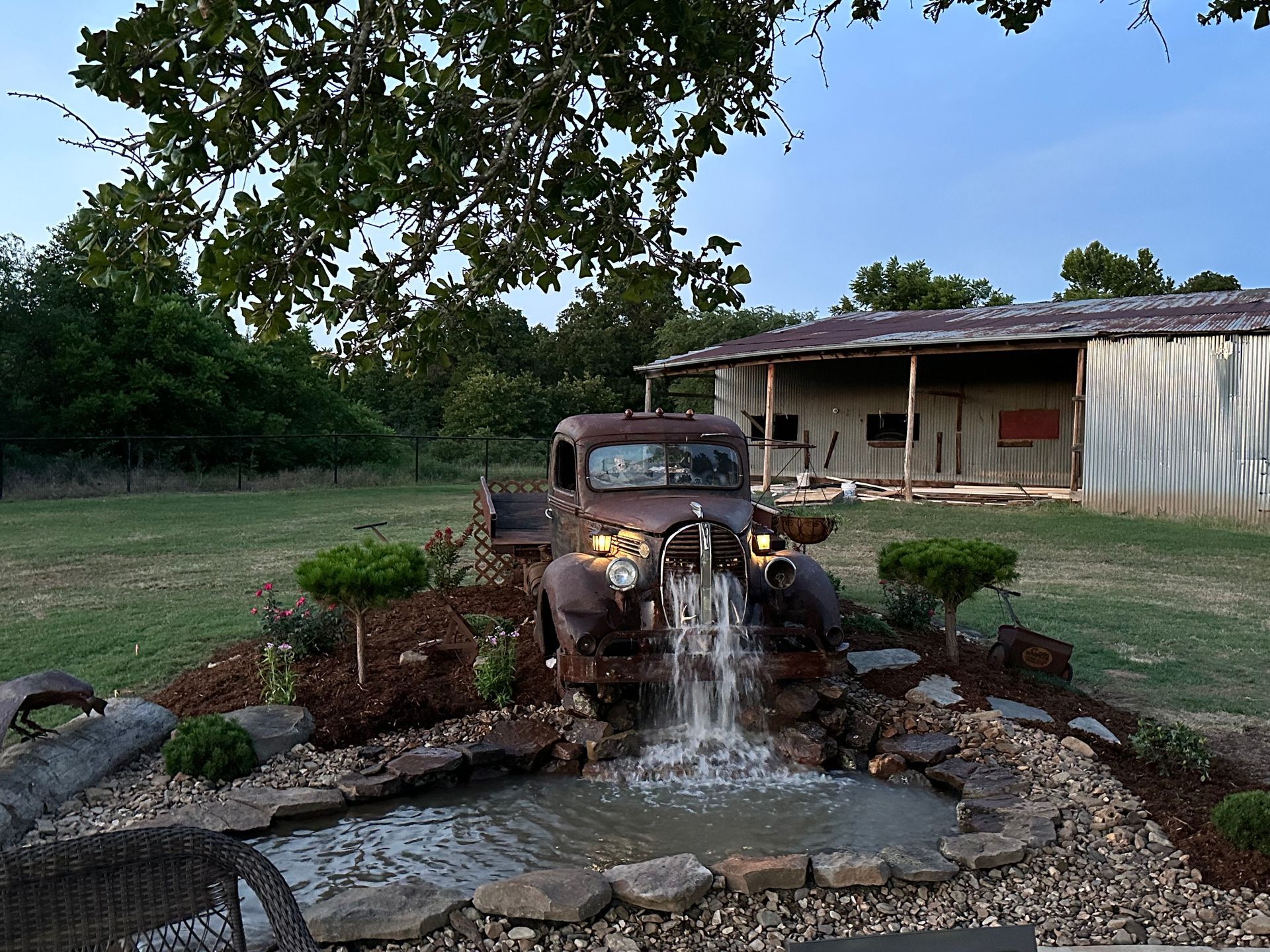 An old truck is parked in front of a waterfall
