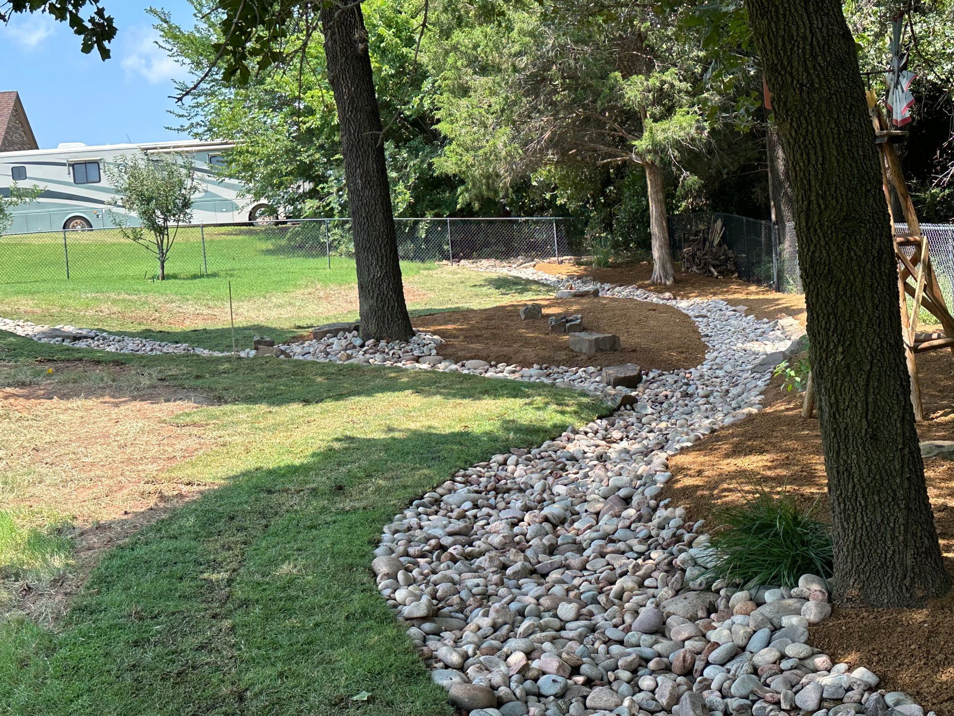 A stream of rocks runs through a lush green field.